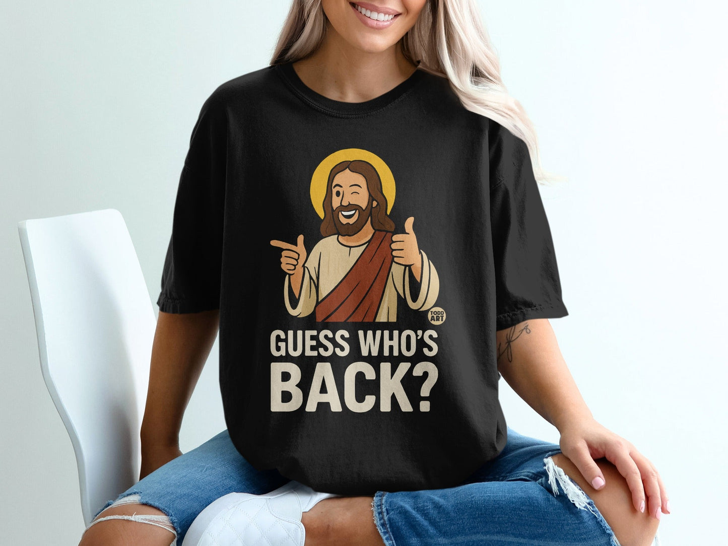 Black t-shirt with "Guess Who's Back?" text and cartoon Jesus giving a thumbs up.