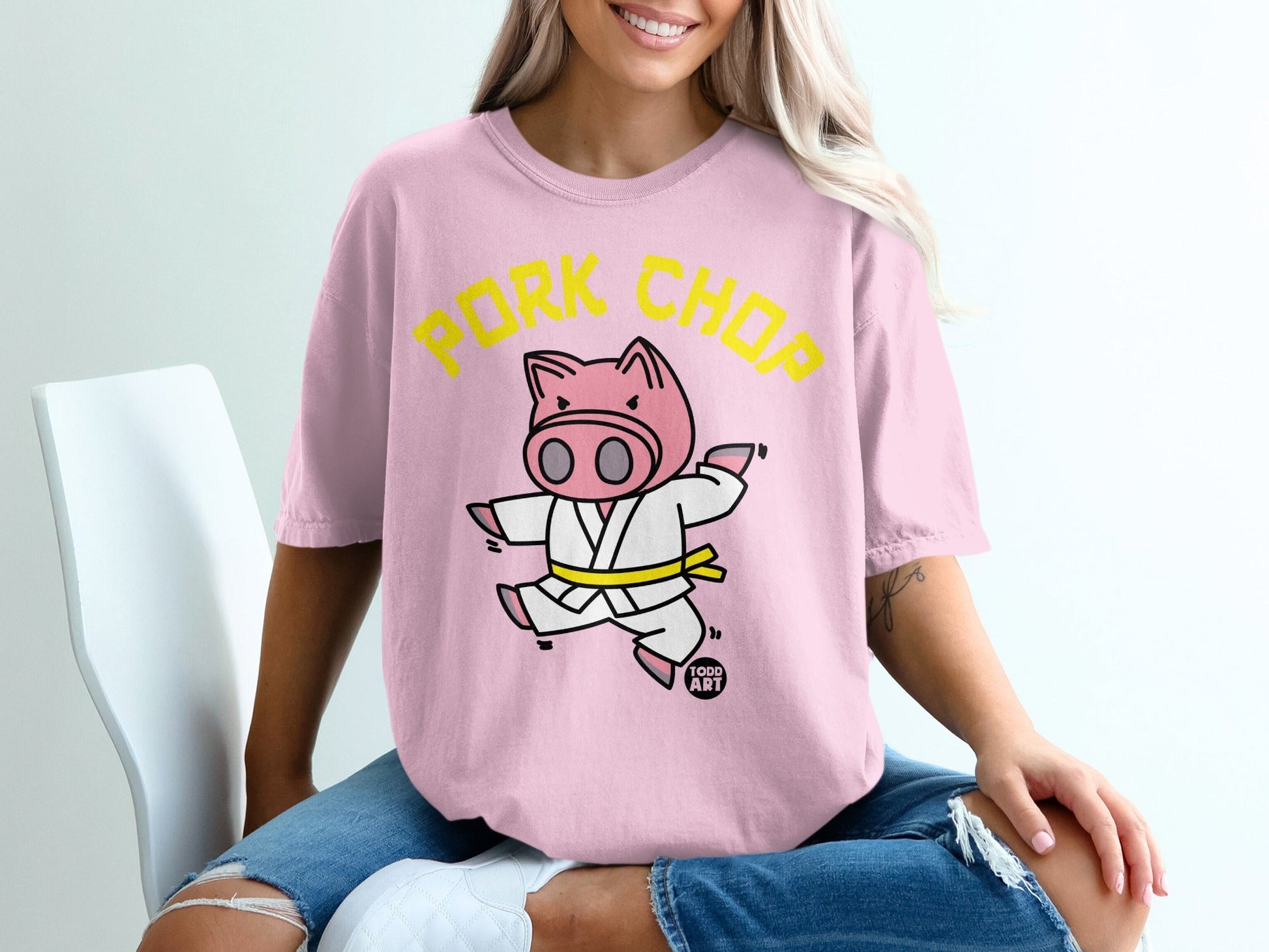 Pink t-shirt with a cartoon pig in a karate gi, wearing a yellow belt.