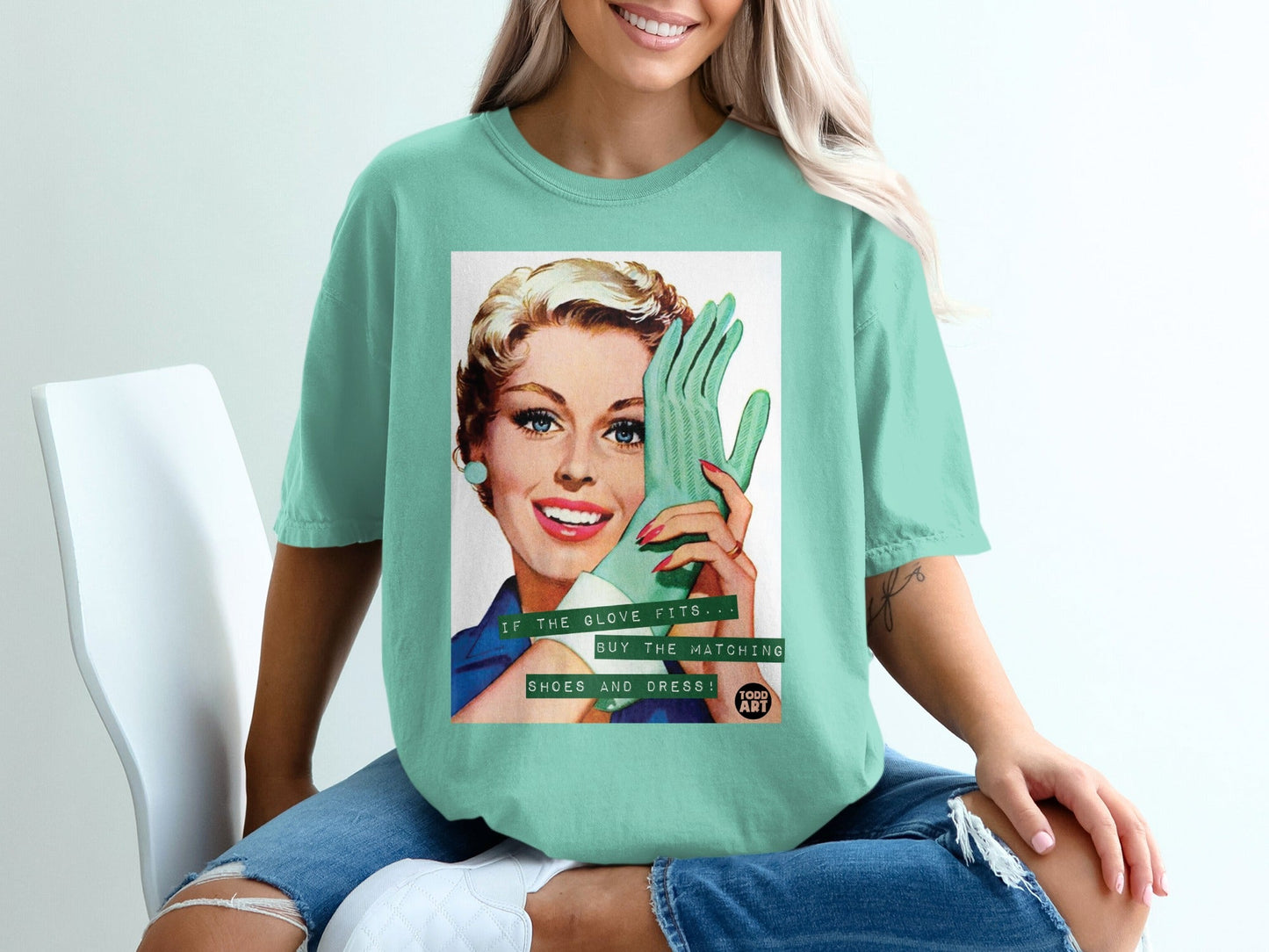 Retro woman in teal t-shirt holding mint green glove, "If the glove fits buy the matching shoes and dress."