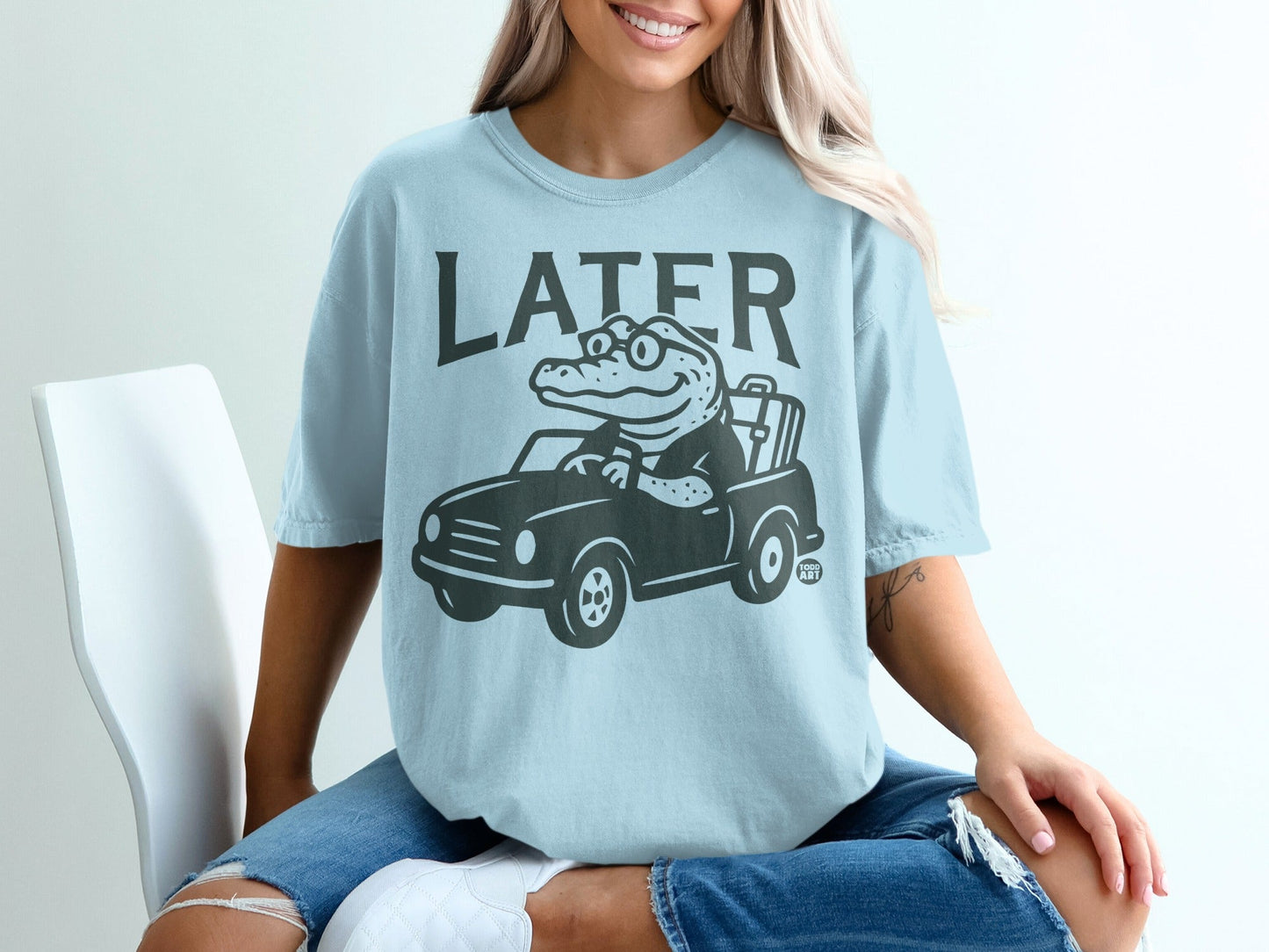 Light blue t-shirt with graphic of alligator driving a car, text "LATER" above.