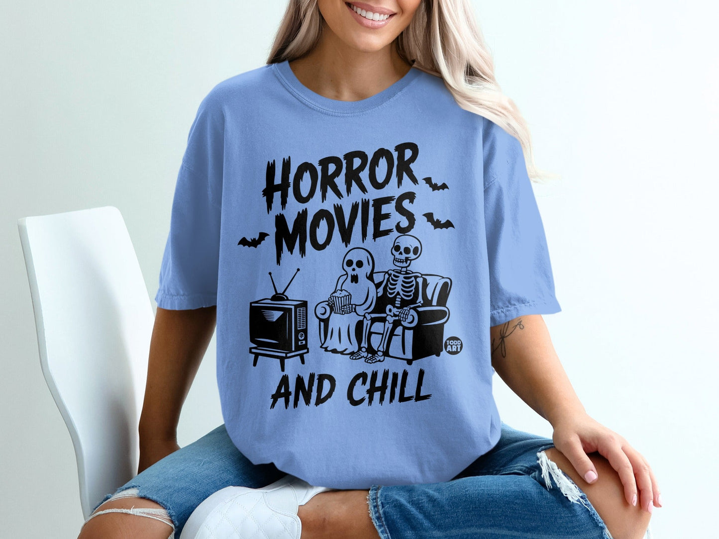 Skeleton and ghost watching TV on couch with text "Horror Movies And Chill".