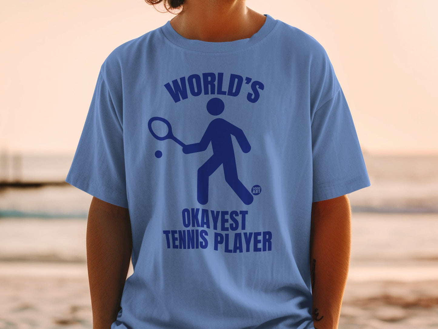 Blue t-shirt with "World's Okayest Tennis Player" graphic.