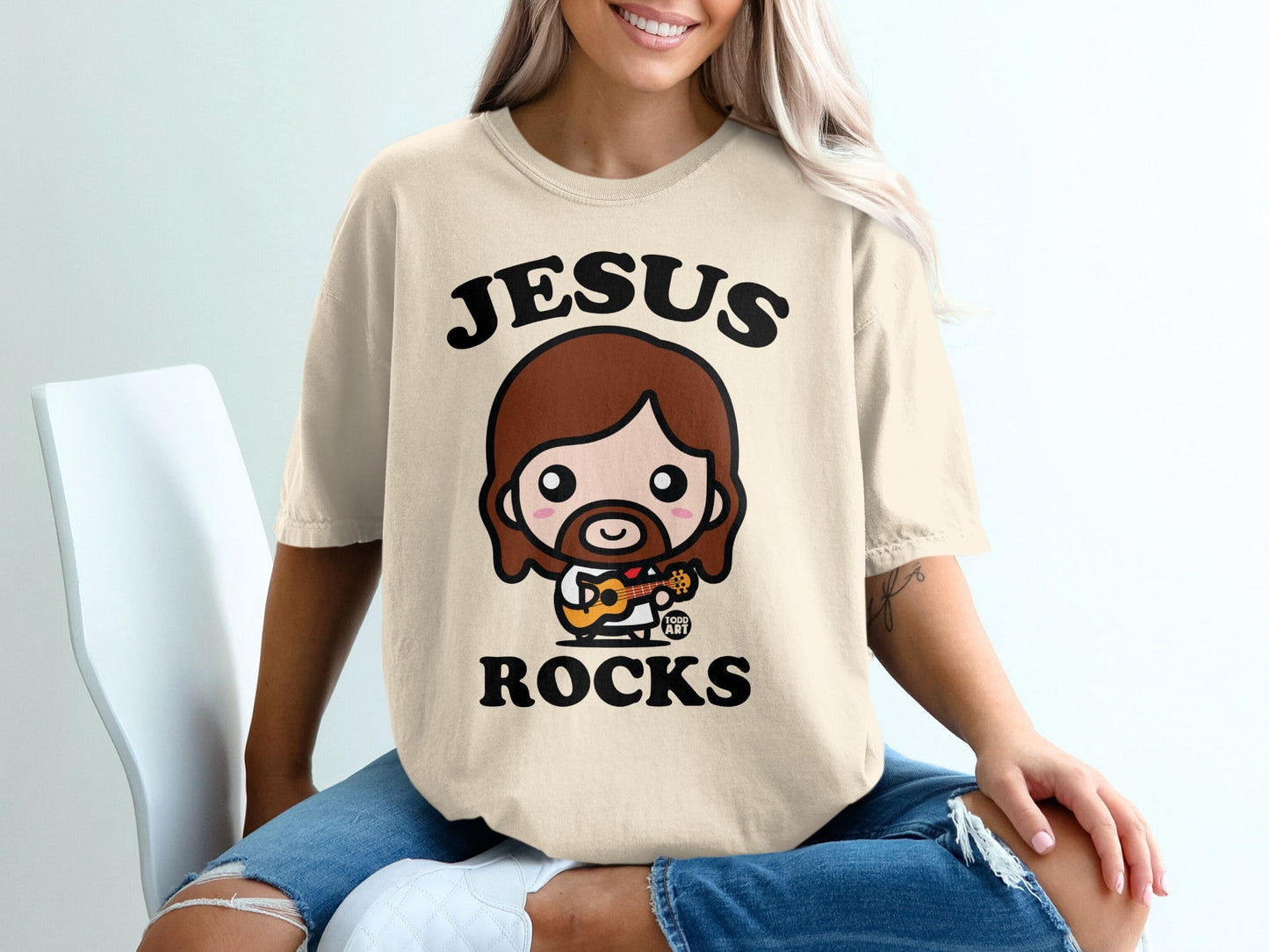 Cute cartoon Jesus with brown hair and beard playing guitar, wearing shirt that says "Jesus Rocks".
