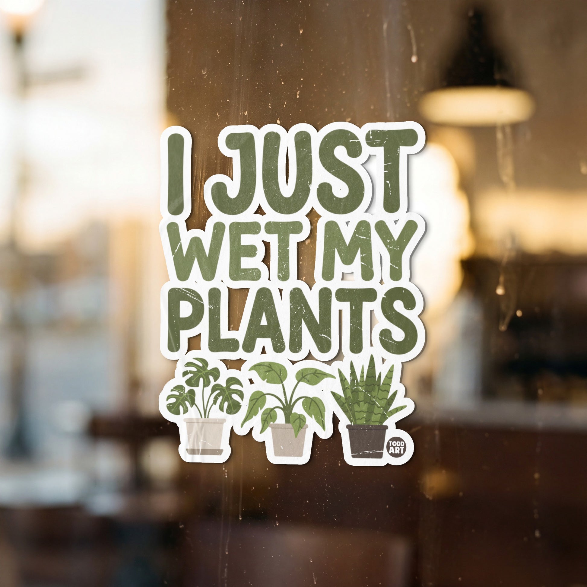 Sticker with green text "I JUST WET MY PLANTS" and three potted plants.
