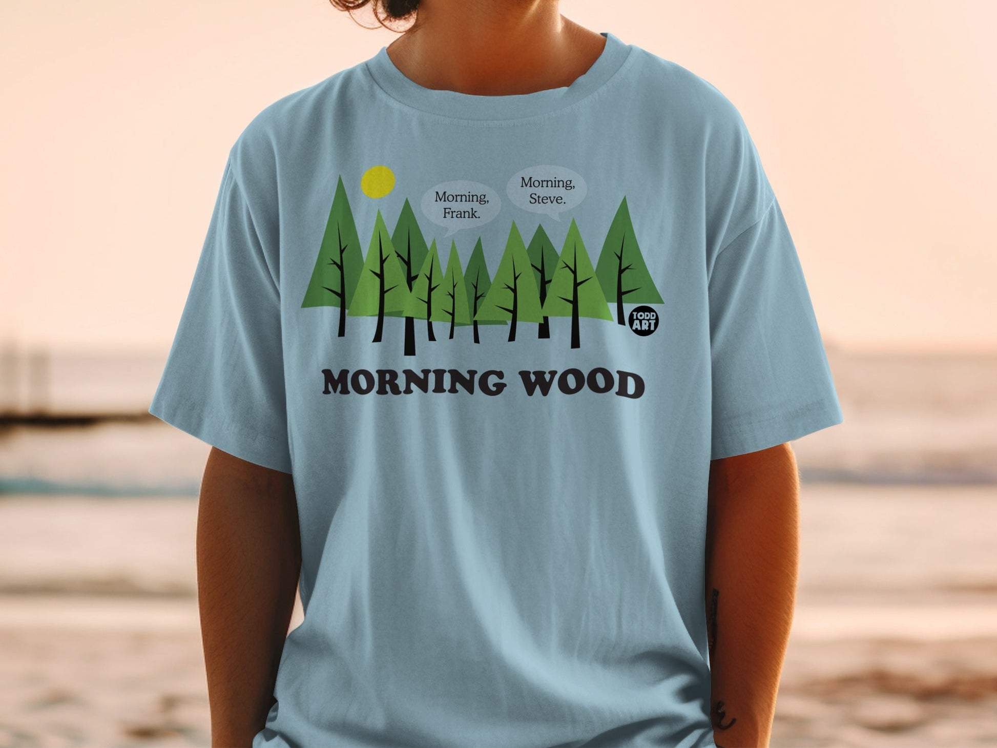 Light blue t-shirt with trees, sun, and "Morning Wood" text with dialogue bubbles.