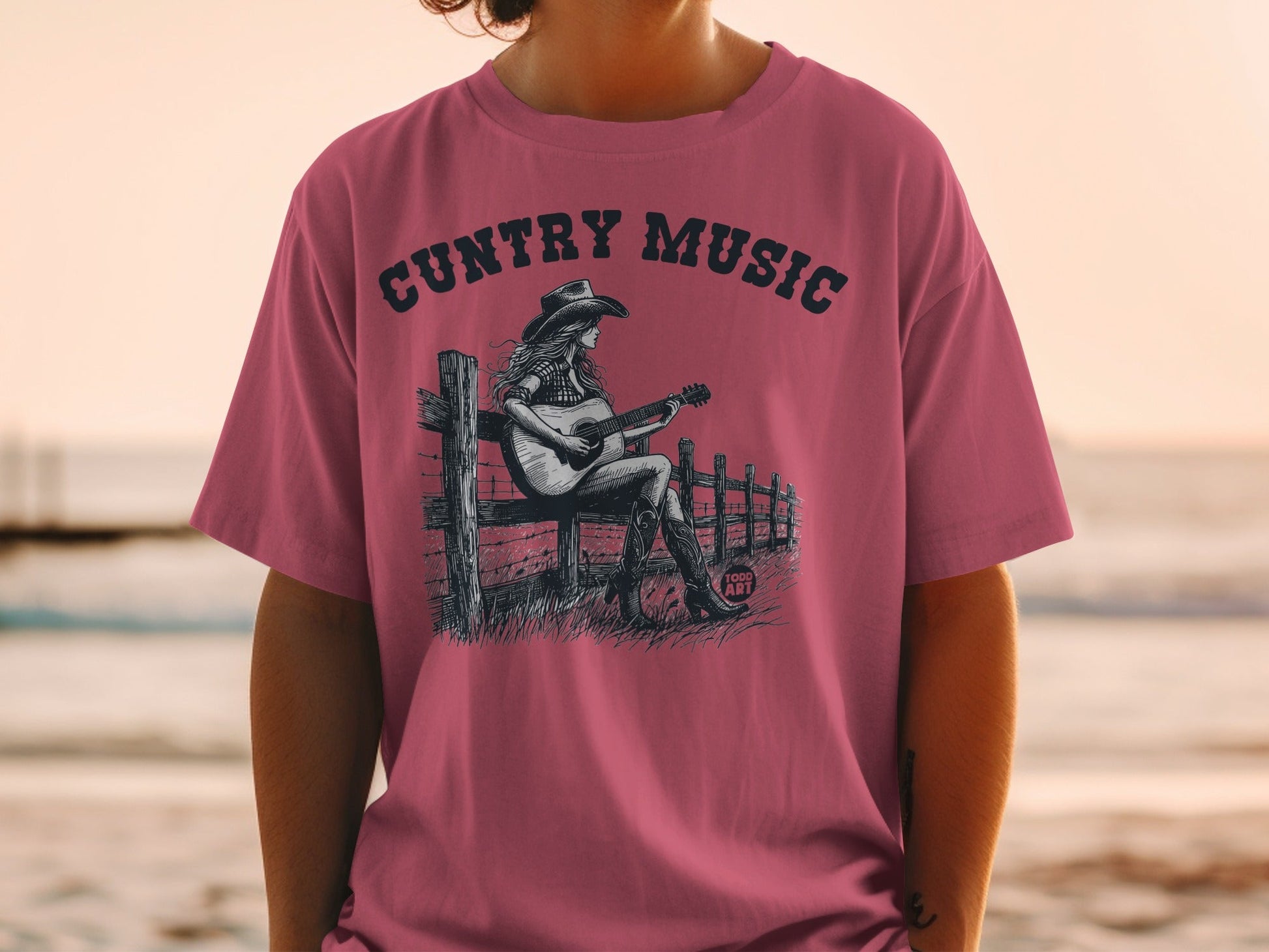 Woman wearing a pink t-shirt with country music graphic.