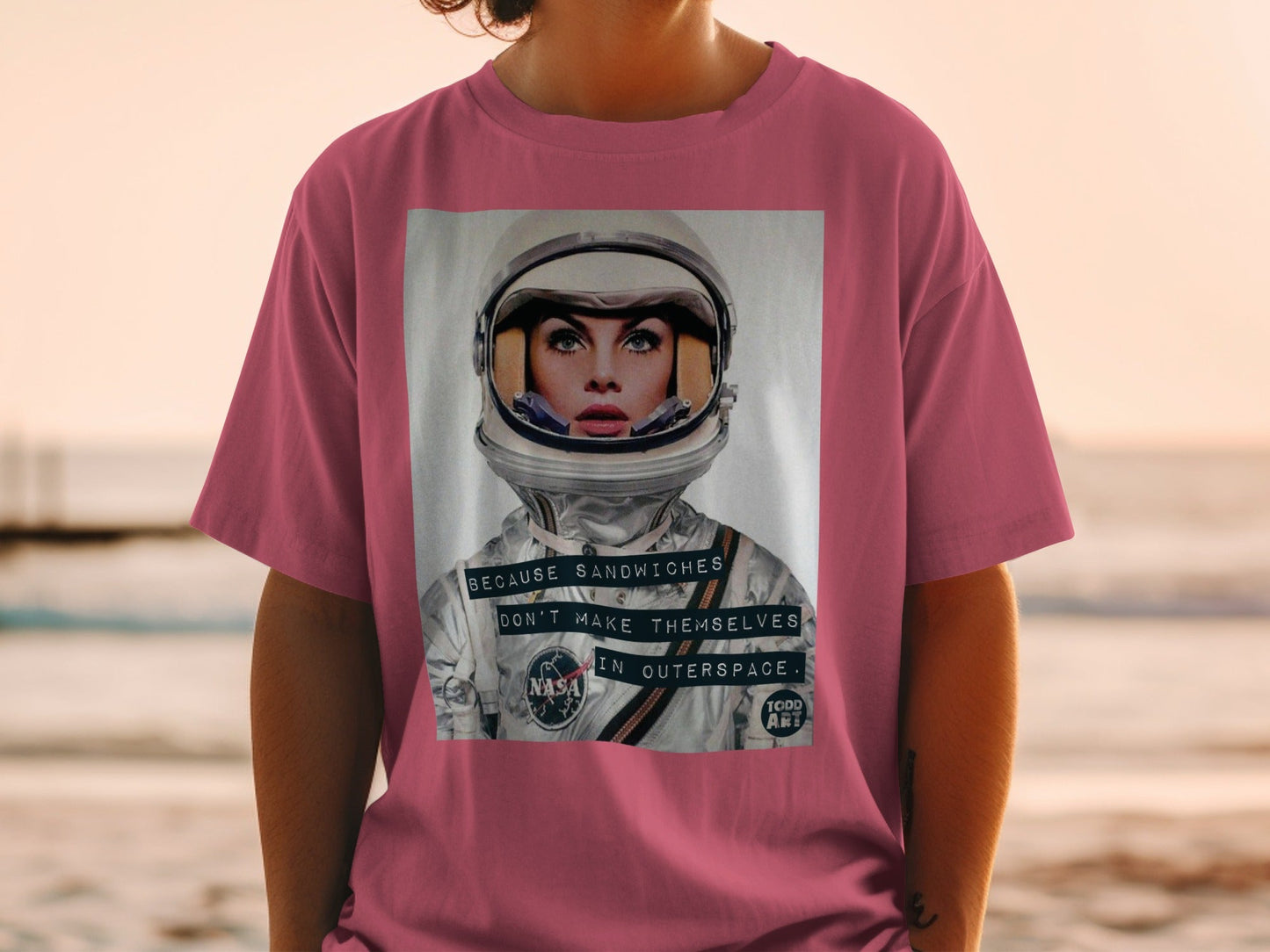 Woman in t-shirt featuring astronaut helmet graphic with text.