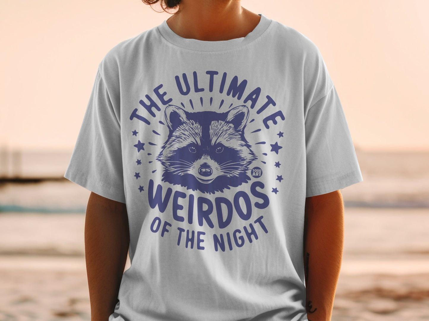 T-shirt with a raccoon graphic and "THE ULTIMATE WEIRDOS OF THE NIGHT" text.