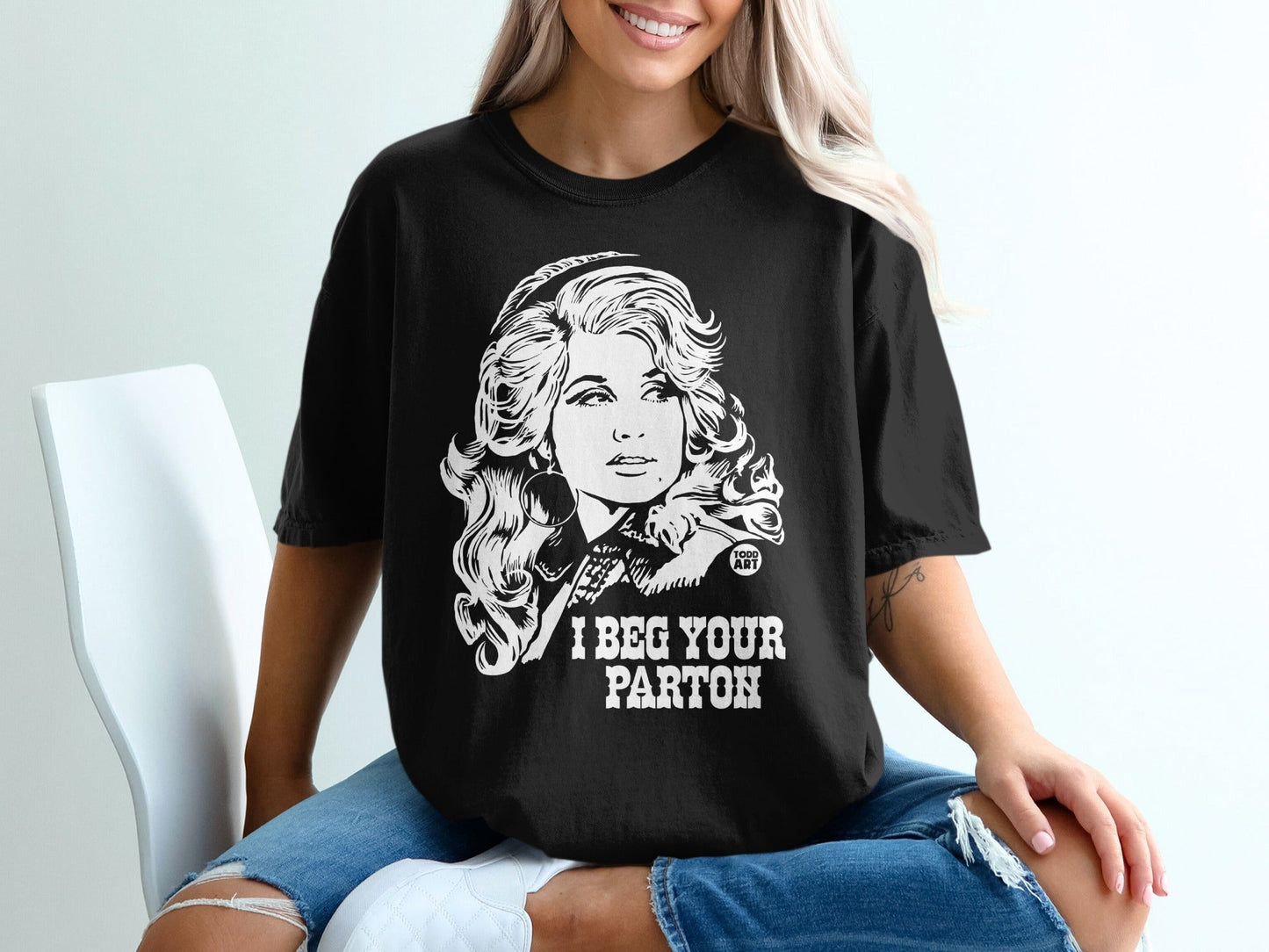 Black t-shirt with portrait of Dolly Parton and text "I BEG YOUR PARTON".