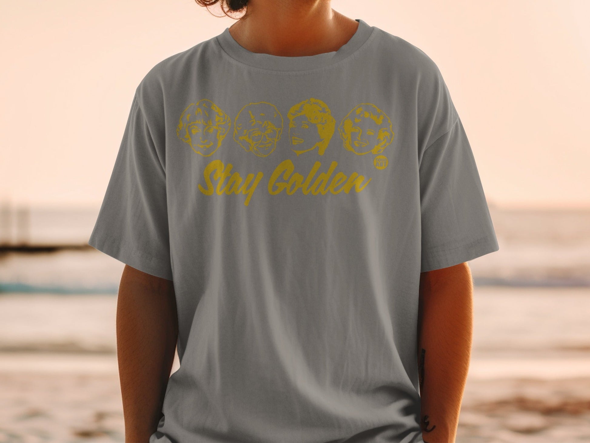 Gray t-shirt with "Stay Golden" and cartoon portraits of The Golden Girls.