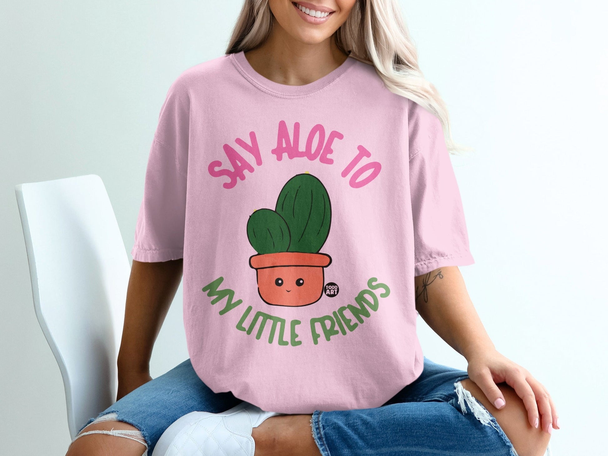 Pink t-shirt with "Say Aloe to My Little Friends" and a smiling cactus in a pot.