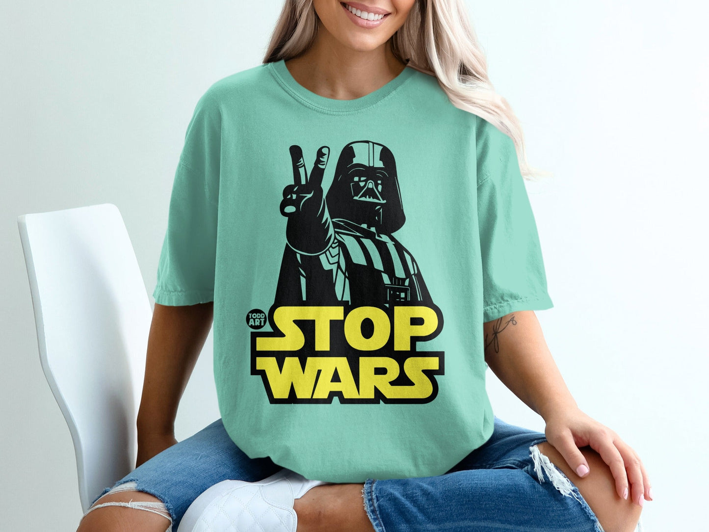Darth Vader giving peace sign above "STOP WARS" text on a mint green t-shirt.