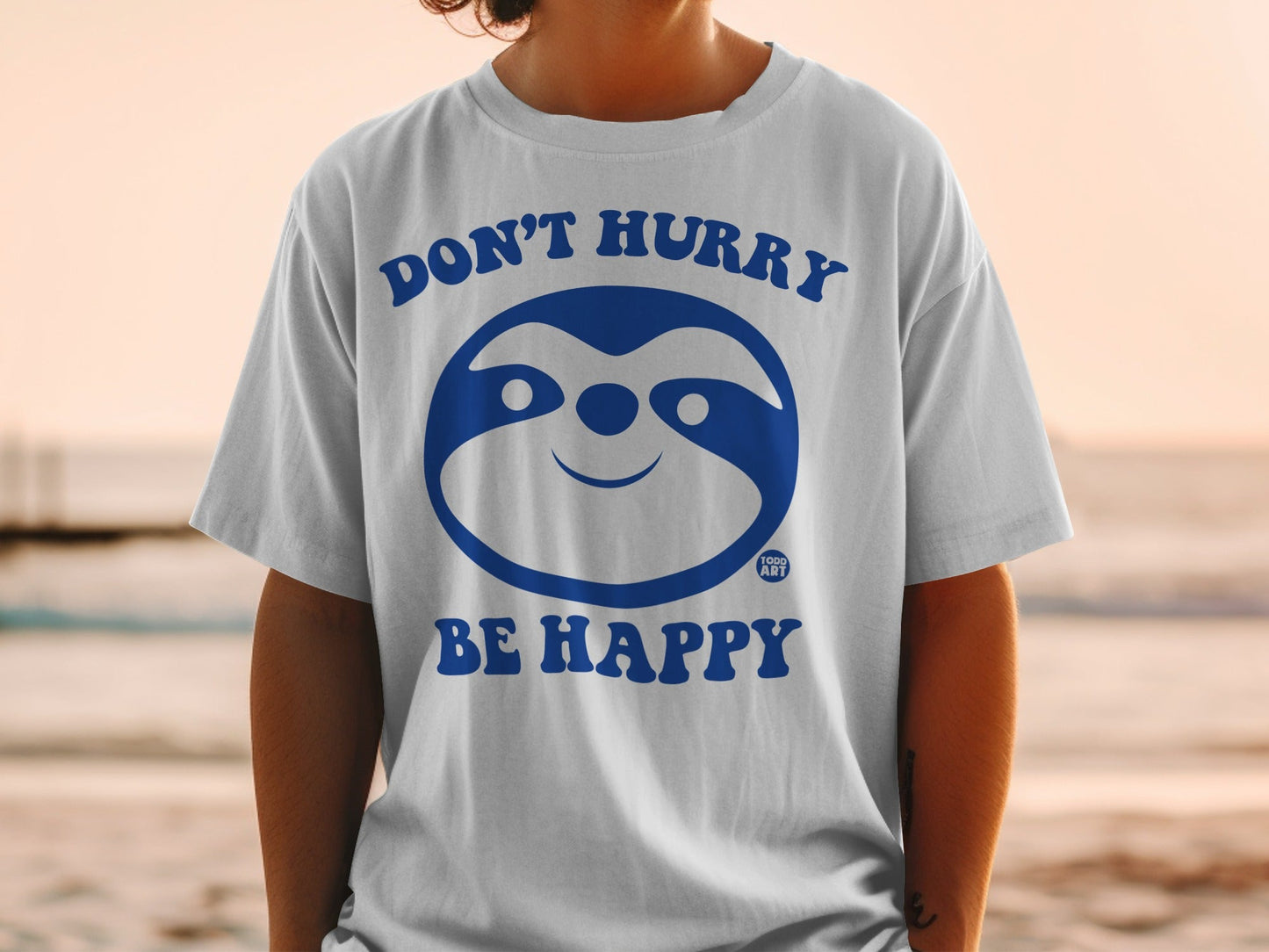 White t-shirt with blue sloth graphic, "DON'T HURRY BE HAPPY" text.