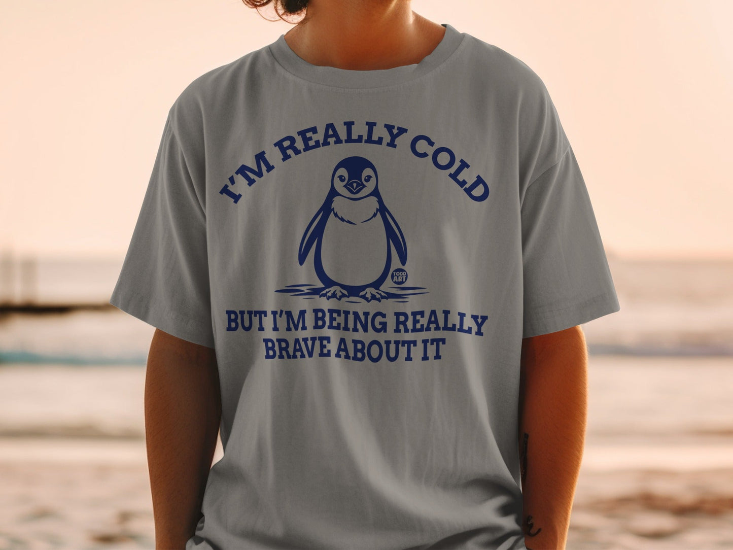 Gray t-shirt with a penguin and text "I'M REALLY COLD BUT I'M BEING REALLY BRAVE ABOUT IT".