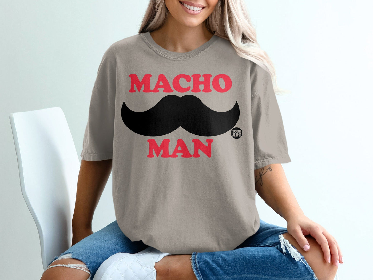 Beige t-shirt with red "MACHO MAN" text and a black mustache graphic.