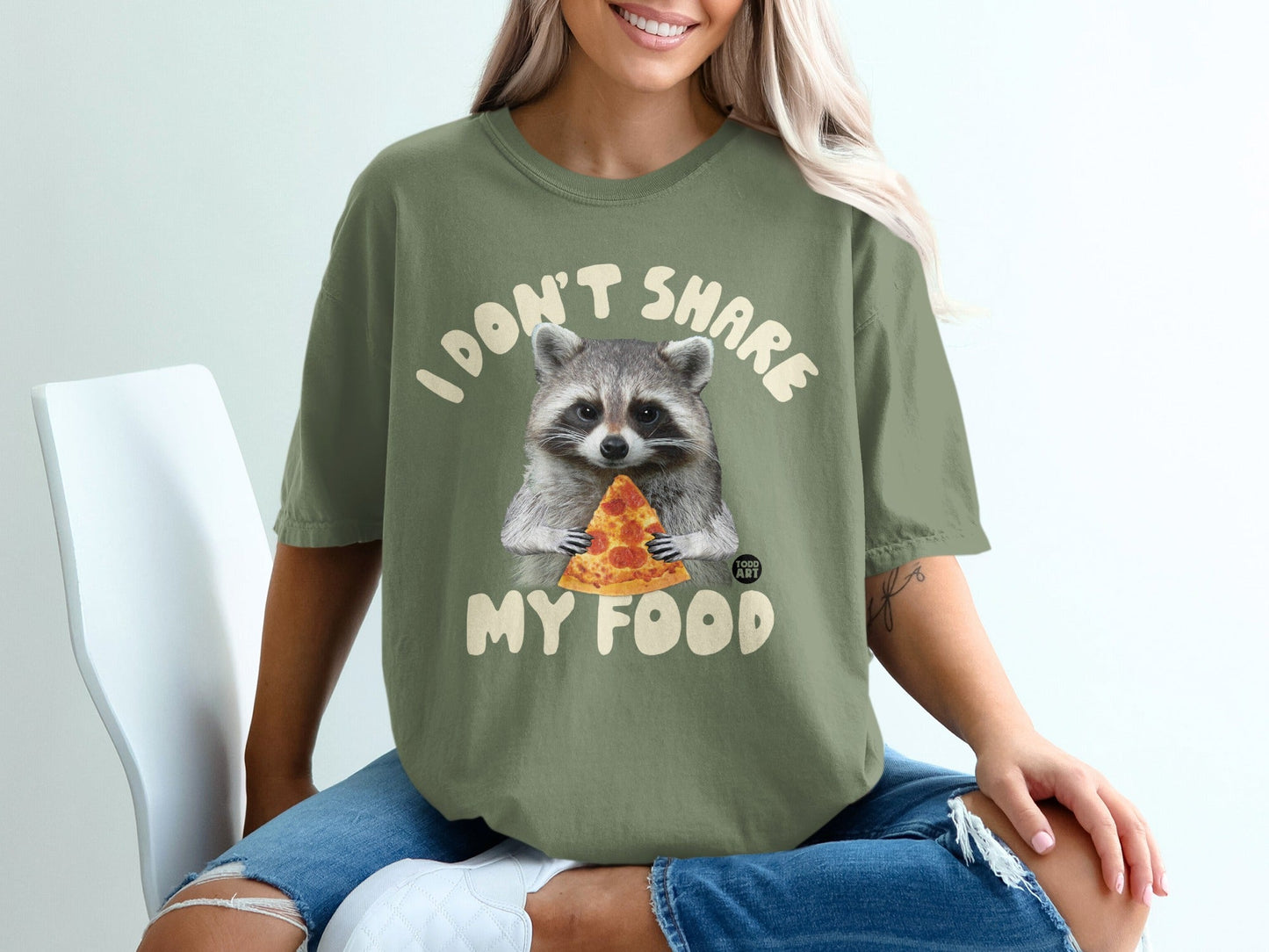 Raccoon holding a slice of pizza on a green t-shirt that reads "I don't share my food".