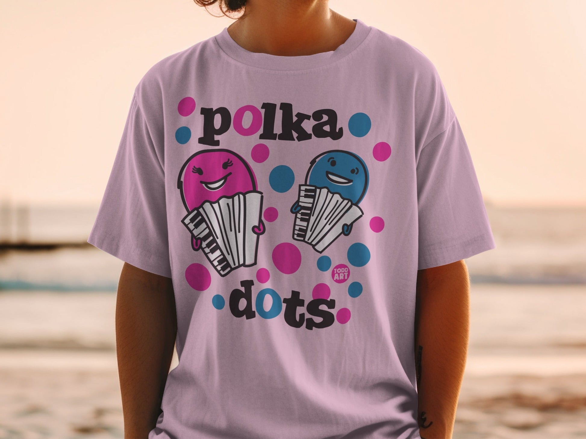 Pink t-shirt with polka dots and smiling cartoon accordions.