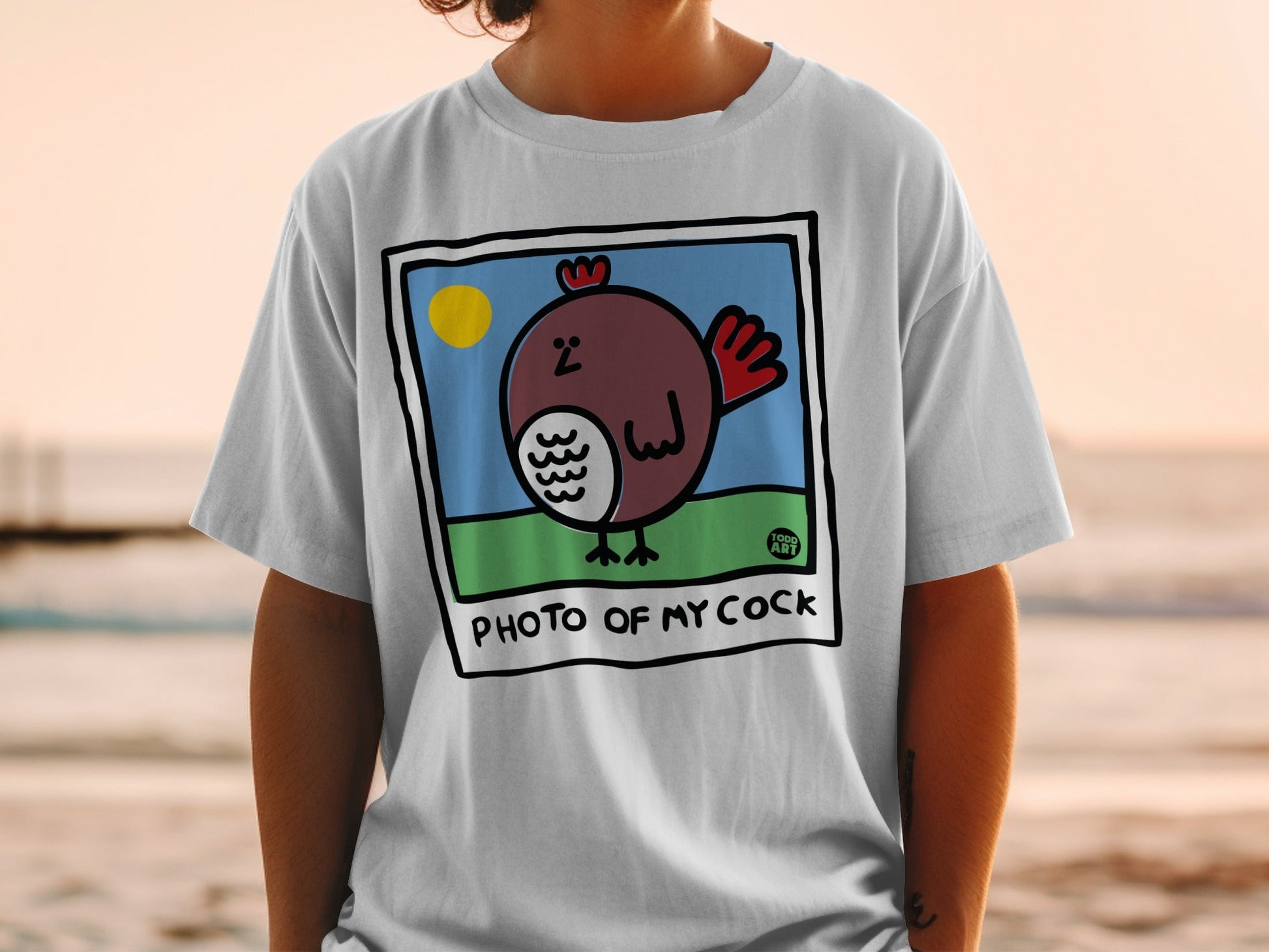 White t-shirt with a cartoon chicken in a frame and the text "PHOTO OF MY COCK".
