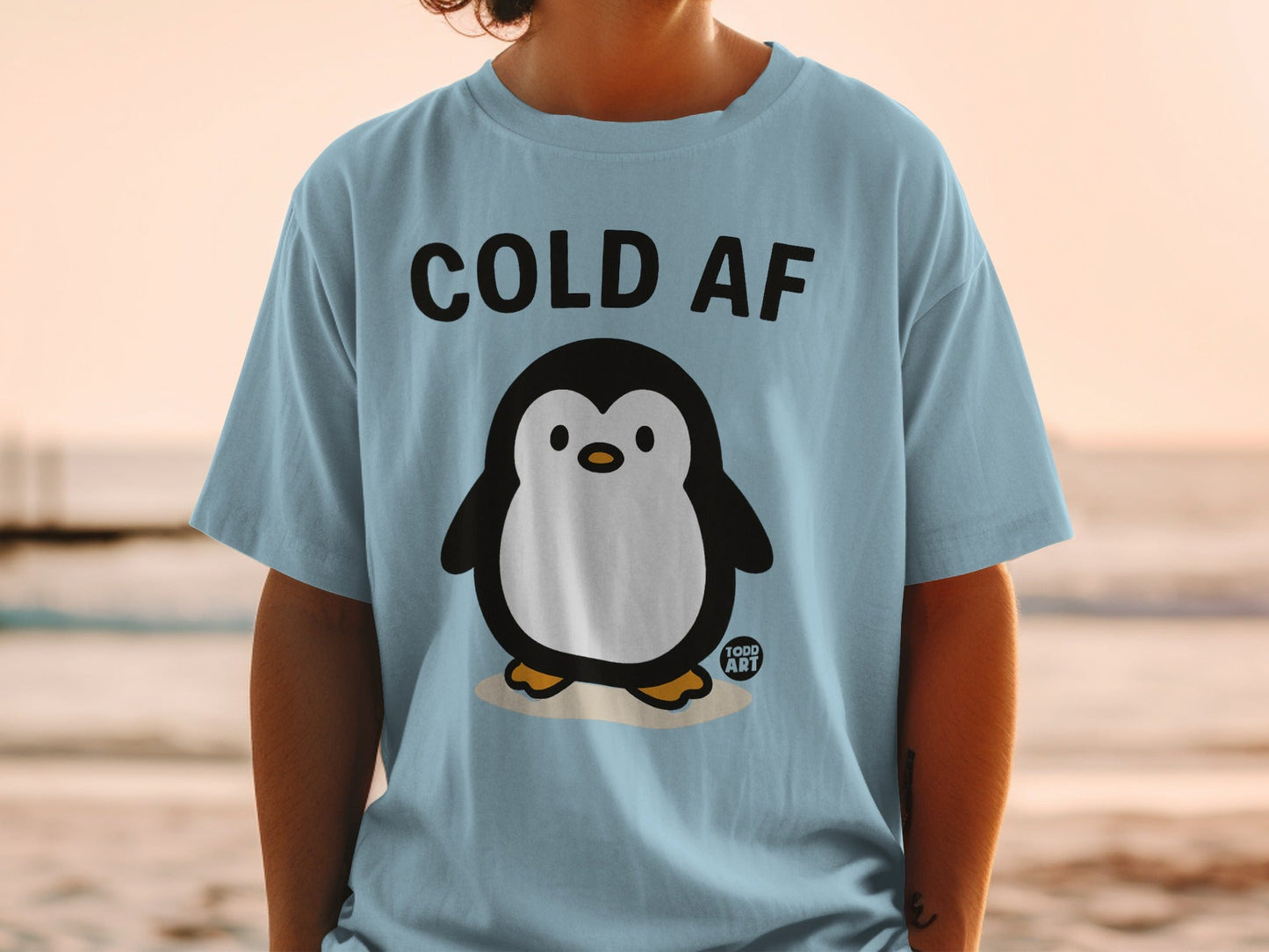 Light blue t-shirt with "COLD AF" text and a cartoon penguin.