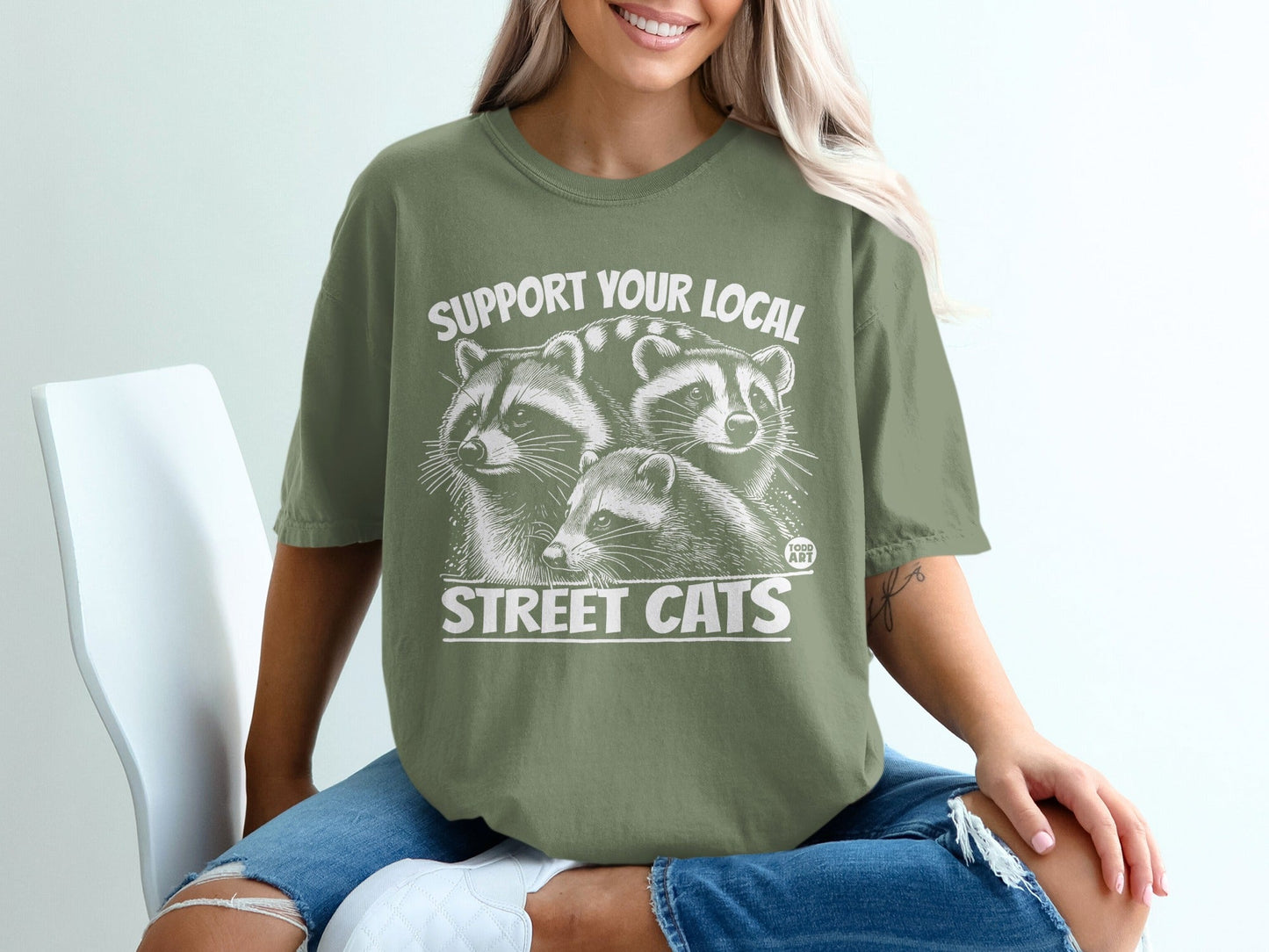 T-shirt with three raccoons and text "SUPPORT YOUR LOCAL STREET CATS".