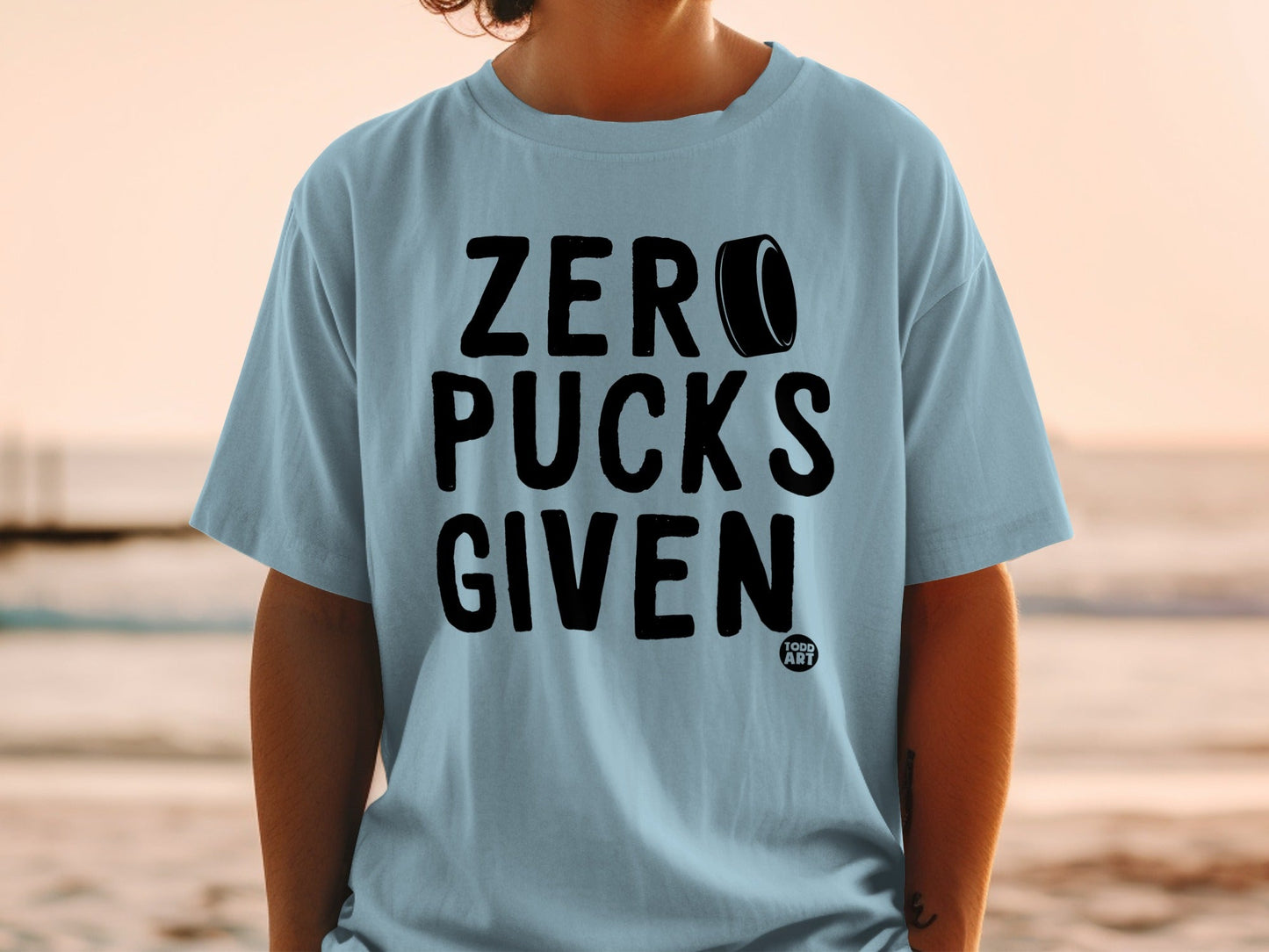 Light blue t-shirt with black text "ZERO PUCKS GIVEN" and a puck logo.