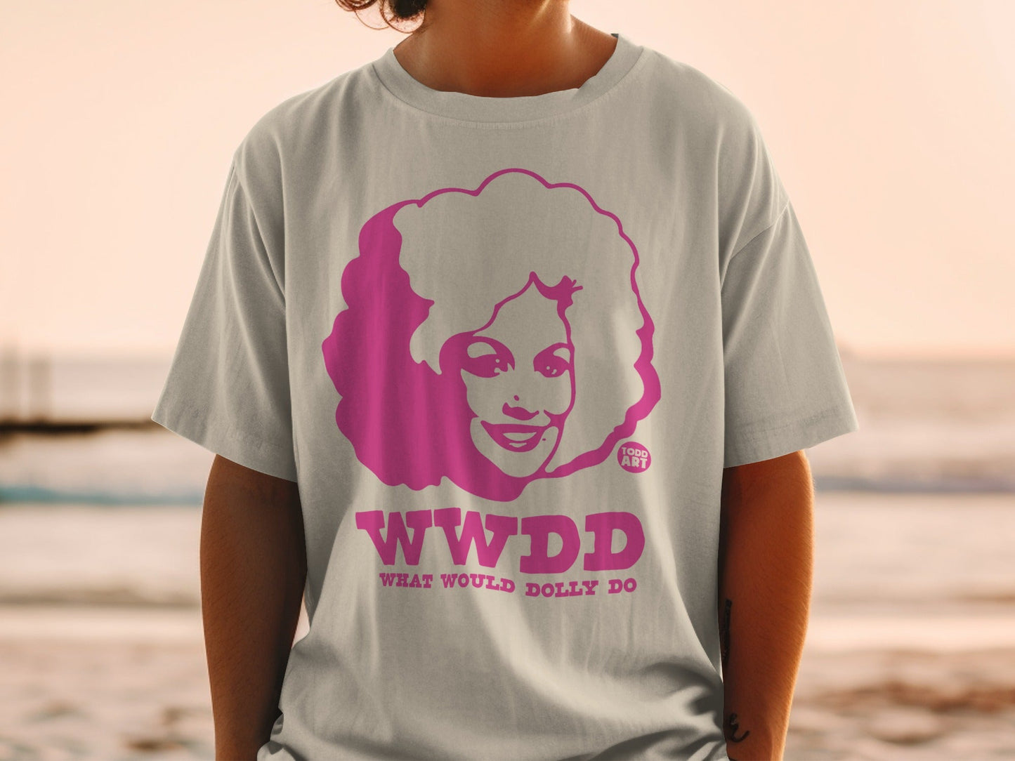 T-shirt with pink WWDD What Would Dolly Do graphic on beige fabric.