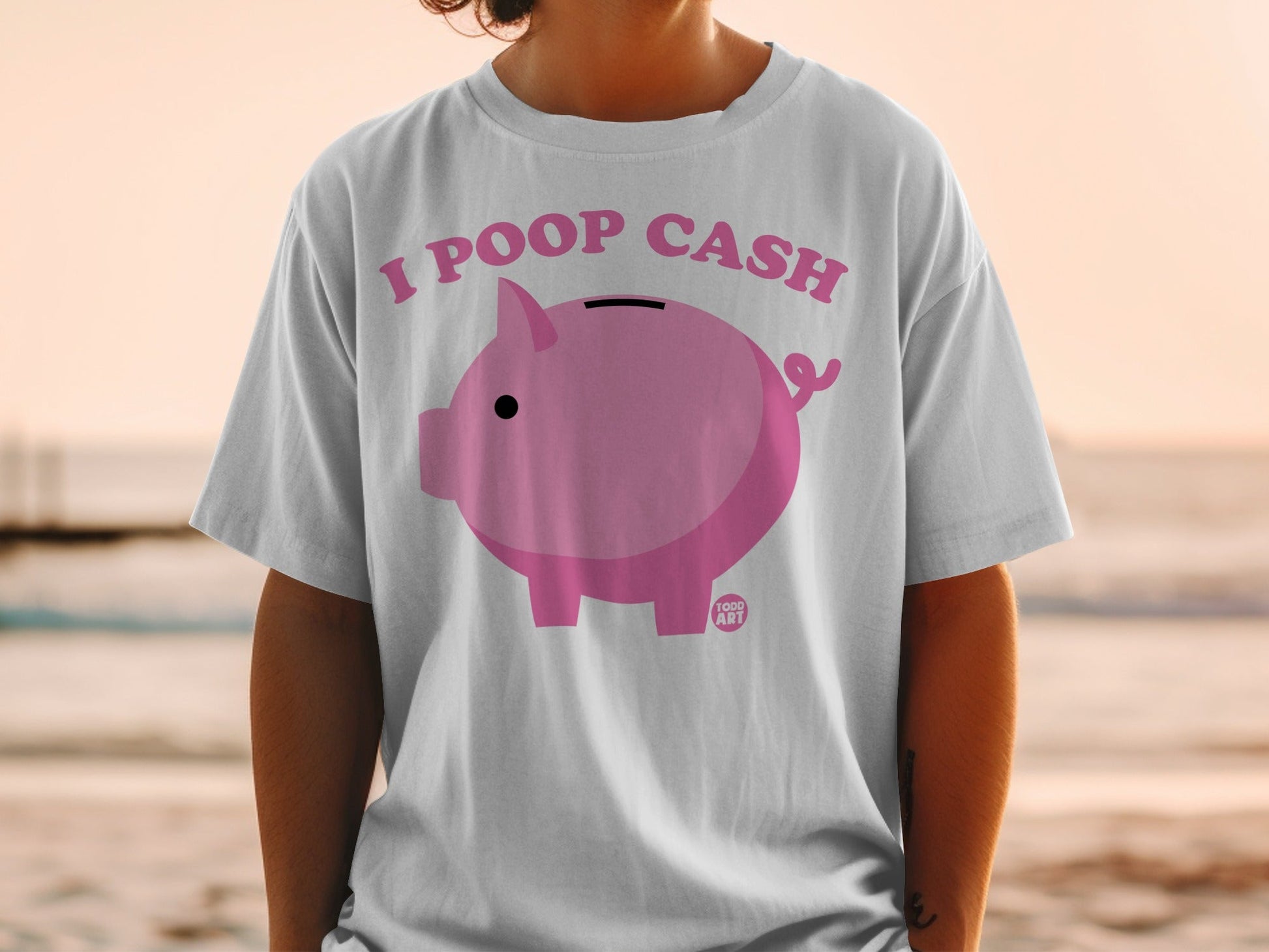 White t-shirt with pink piggy bank graphic and "I POOP CASH" text.