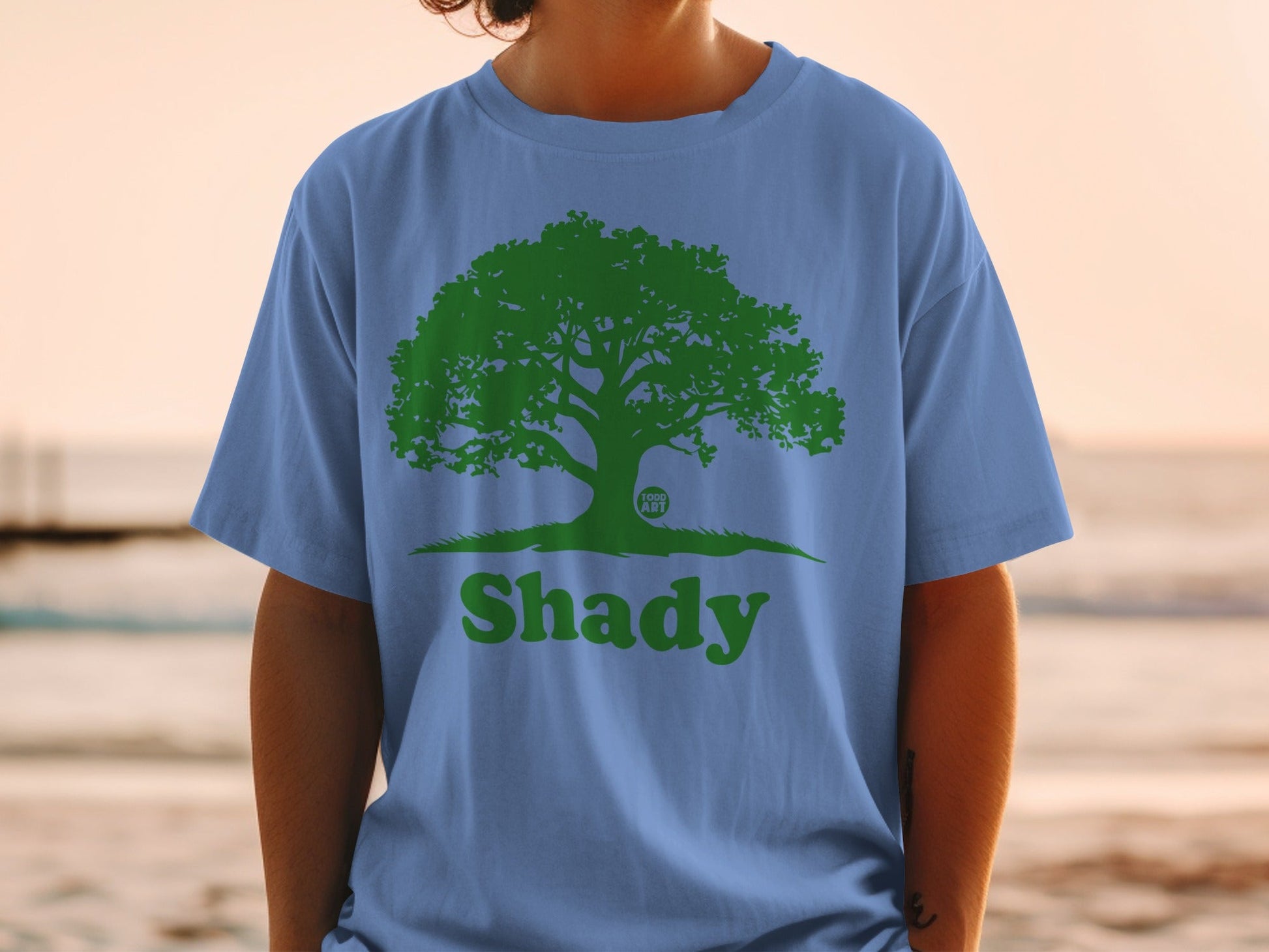 Blue t-shirt with green tree logo and "Shady" text.