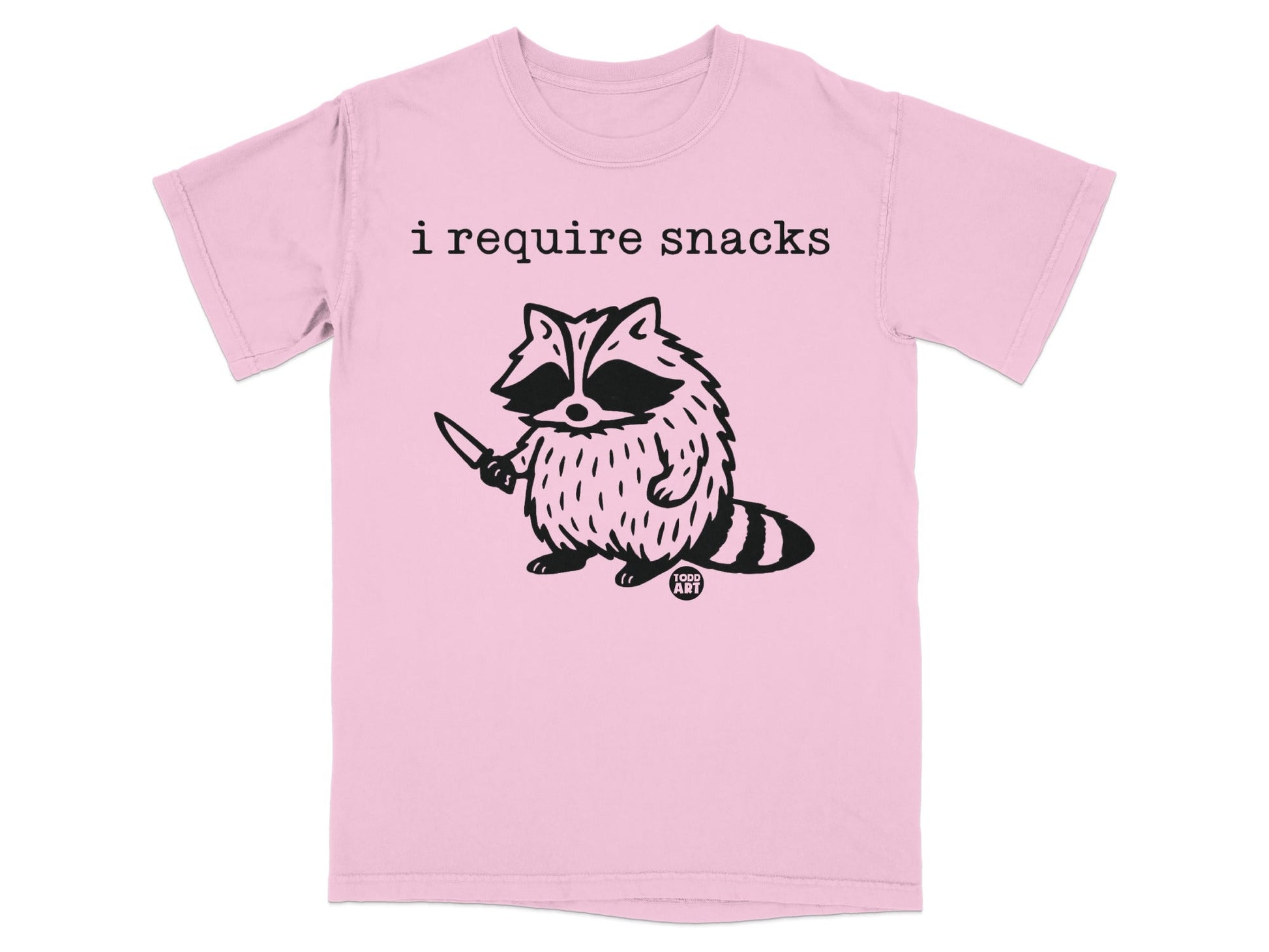 Pink t-shirt with black raccoon illustration and "i require snacks" text.