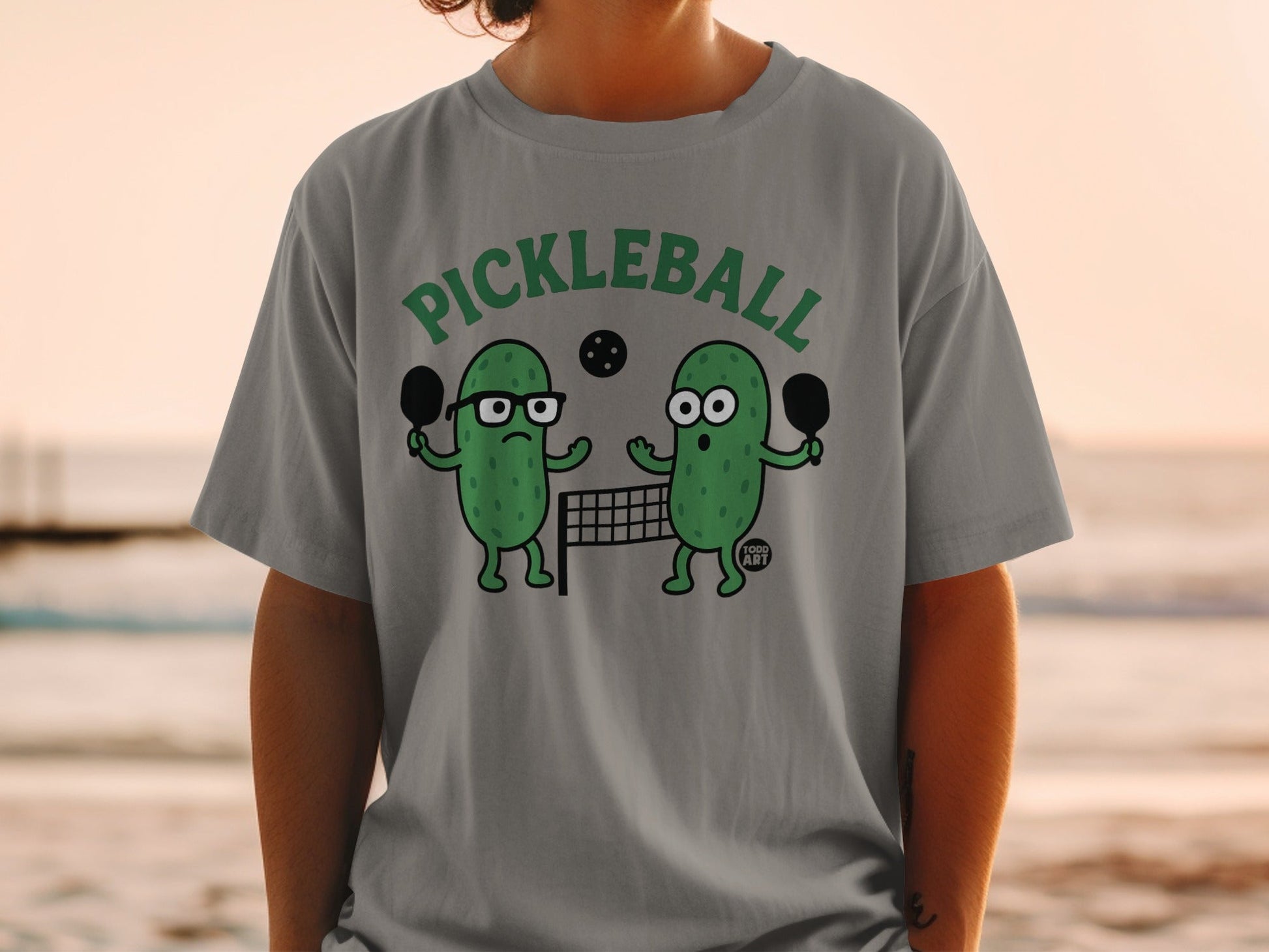 Cartoon pickle characters playing pickleball on a net.