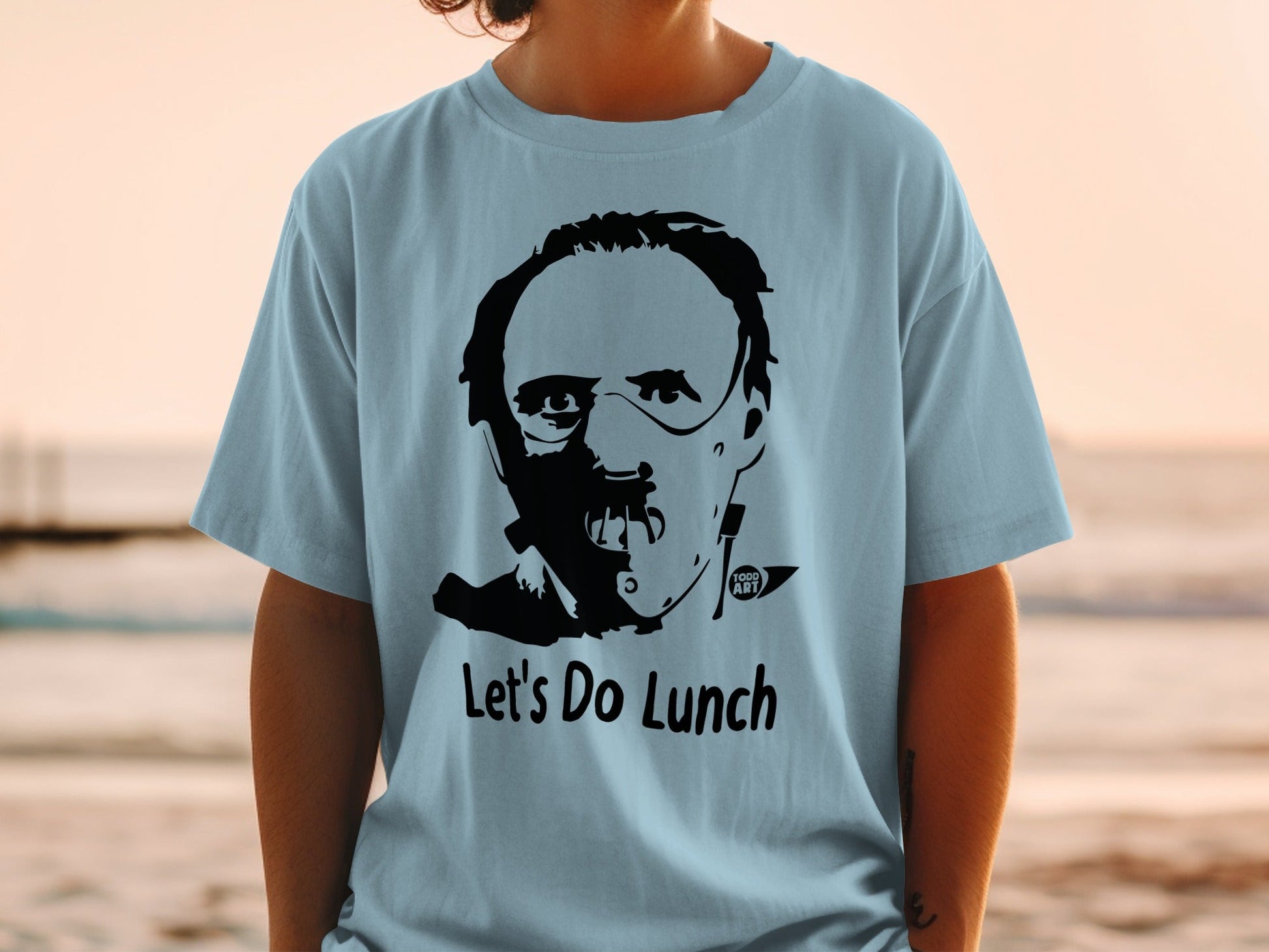 Light blue t-shirt with black graphic of Hannibal Lecter's face and "Let's Do Lunch".