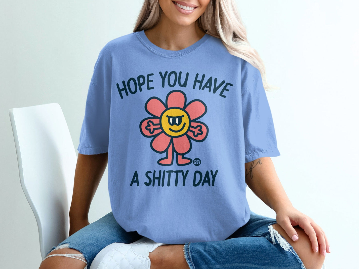 Blue t-shirt with a smiling flower graphic and the text "HOPE YOU HAVE A SHITTY DAY".