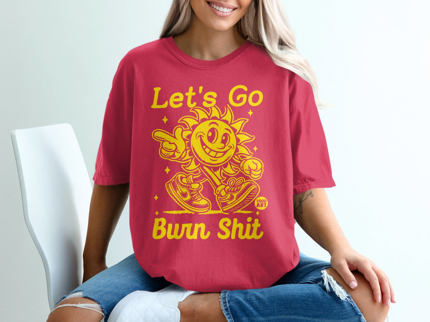 Red t-shirt with yellow text "Let's Go Burn Shit" and smiling sun graphic.