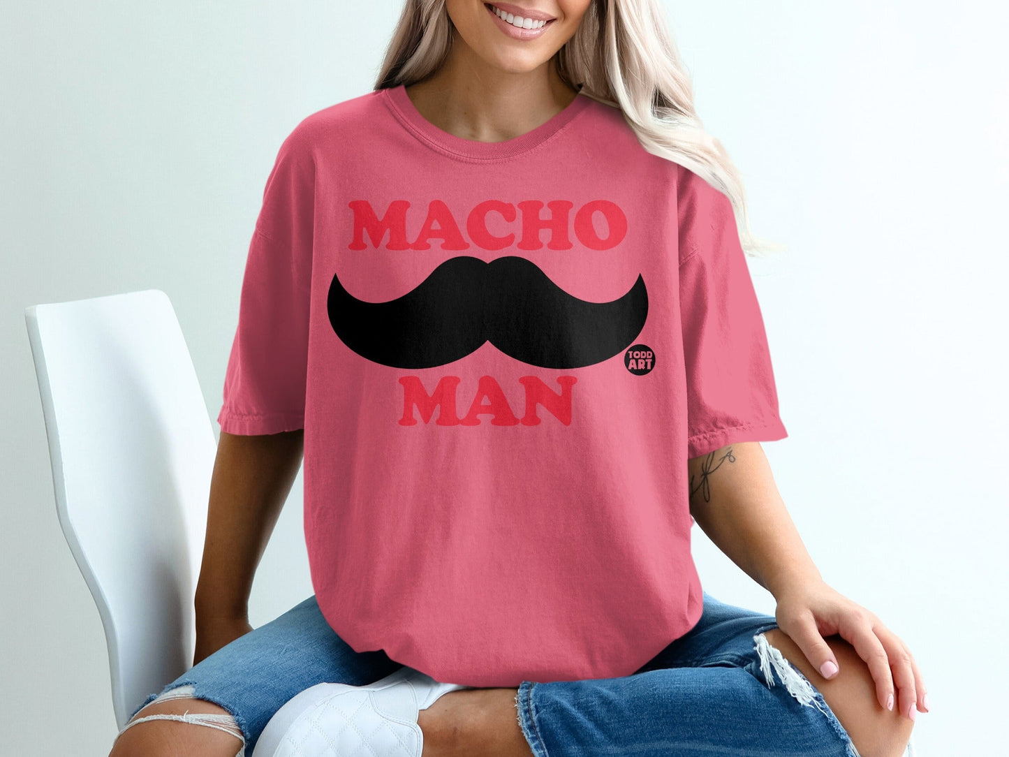Pink t-shirt with red "MACHO MAN" text and black mustache.