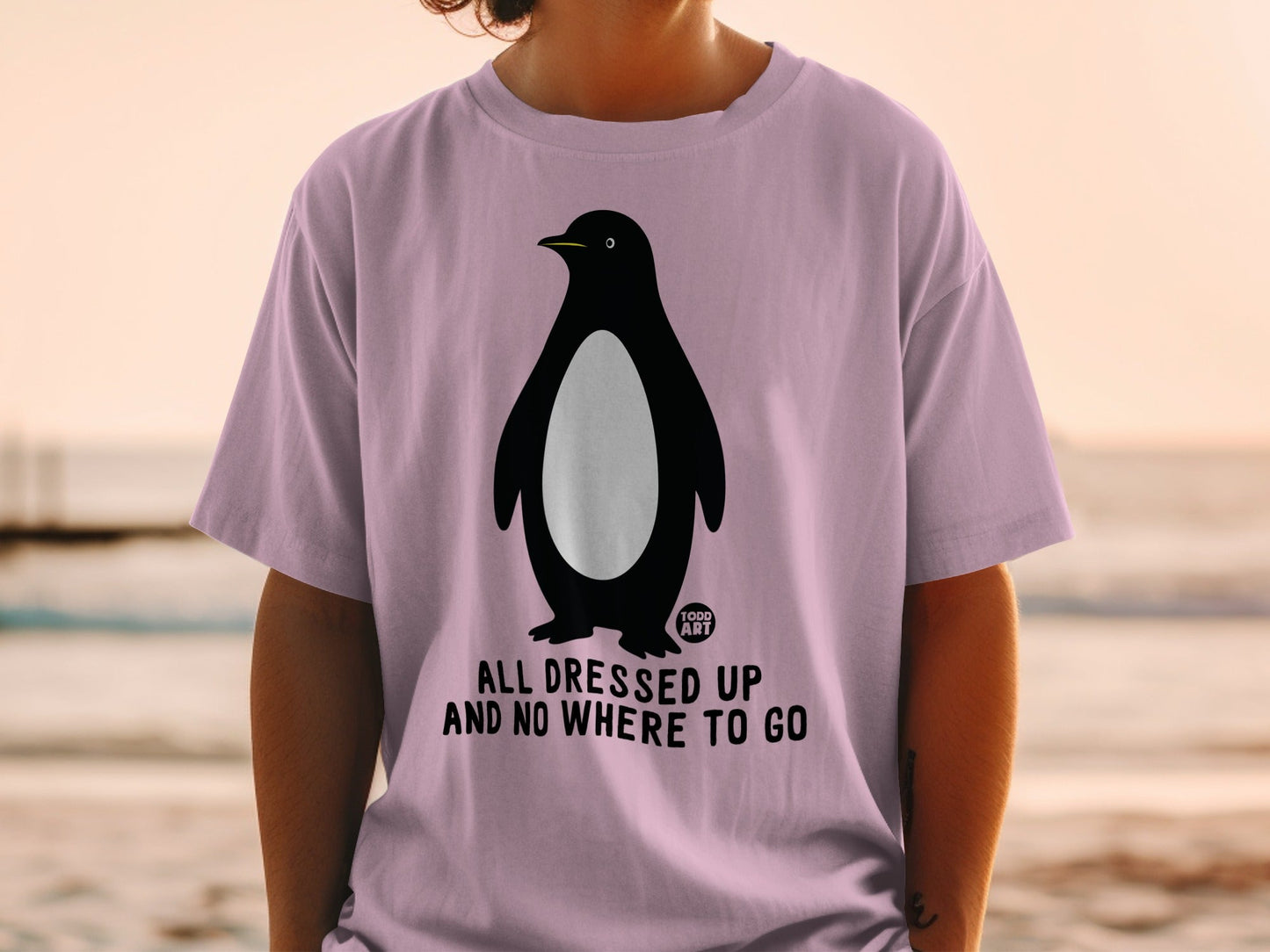 Pink t-shirt with a penguin graphic and text "ALL DRESSED UP AND NO WHERE TO GO".