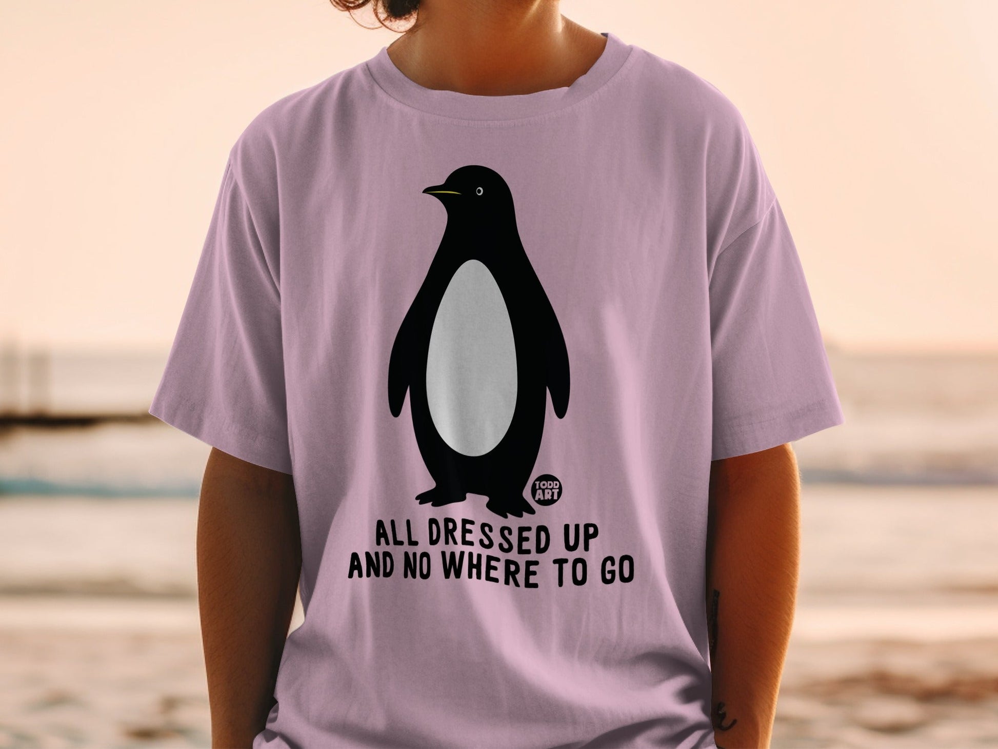 Pink t-shirt with a penguin graphic and text "ALL DRESSED UP AND NO WHERE TO GO".