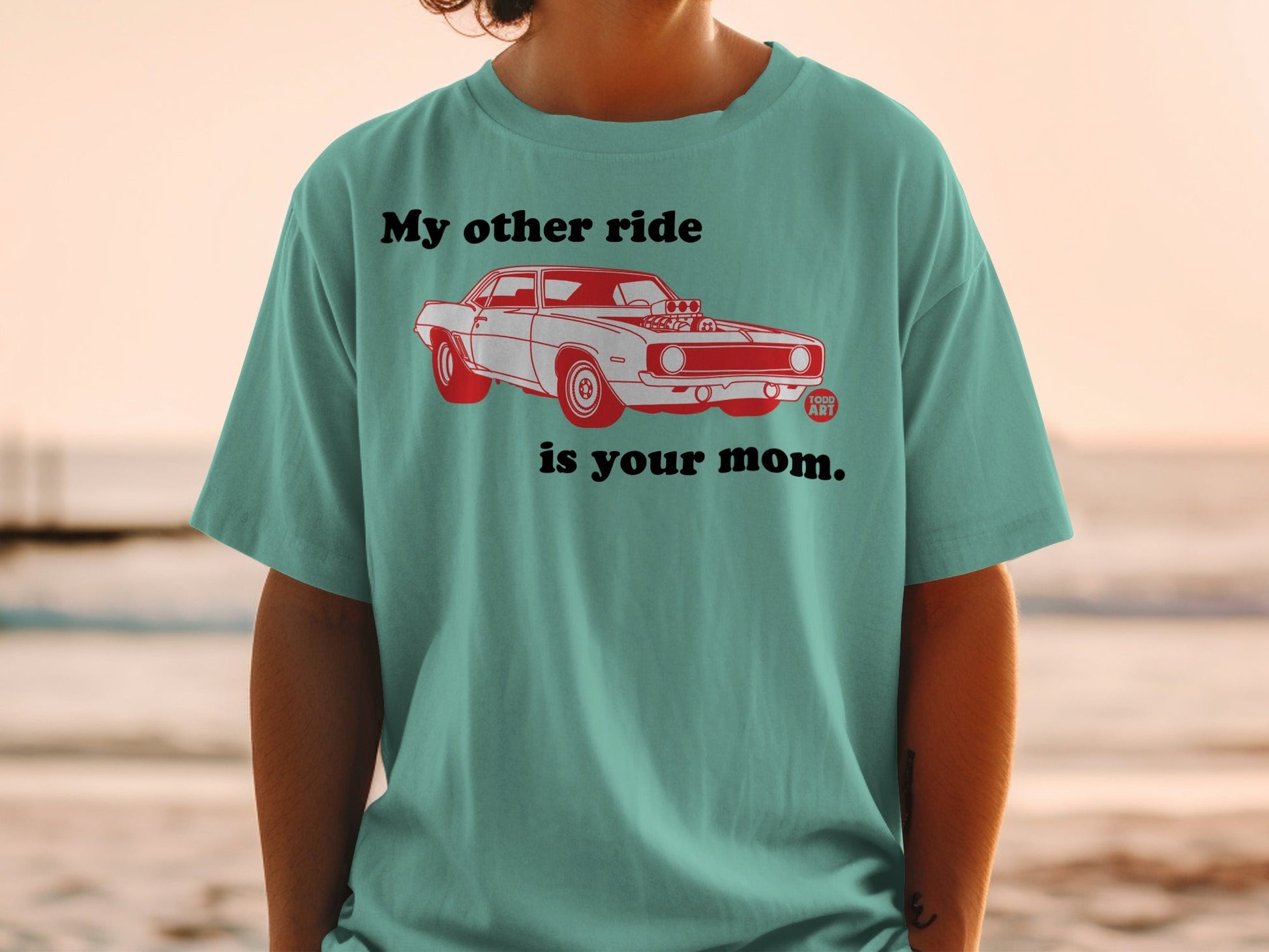 Teal t-shirt with red illustration of a vintage car and text "My other ride is your mom."
