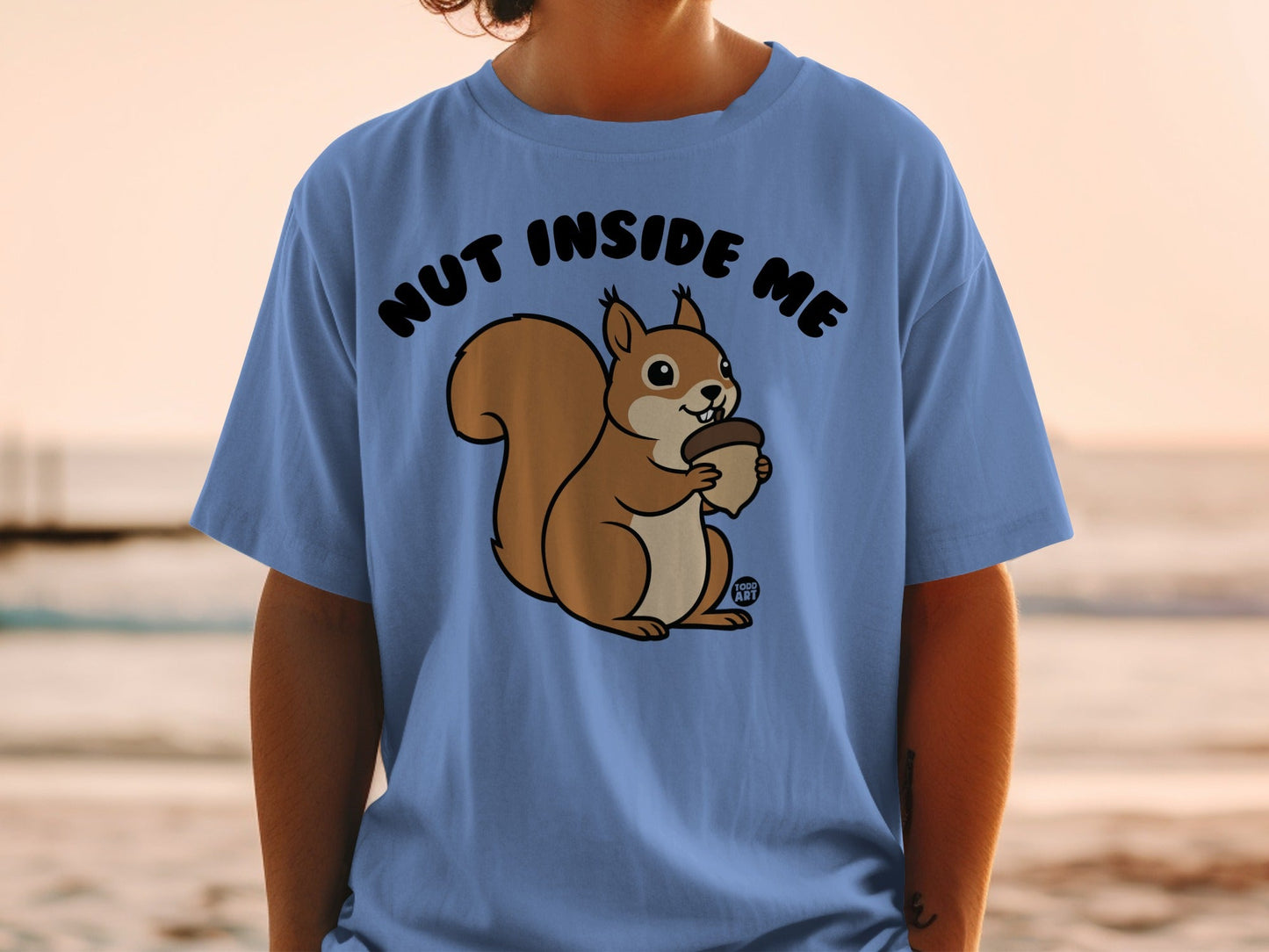 Blue t-shirt with cartoon squirrel holding acorn, text "NUT INSIDE ME".