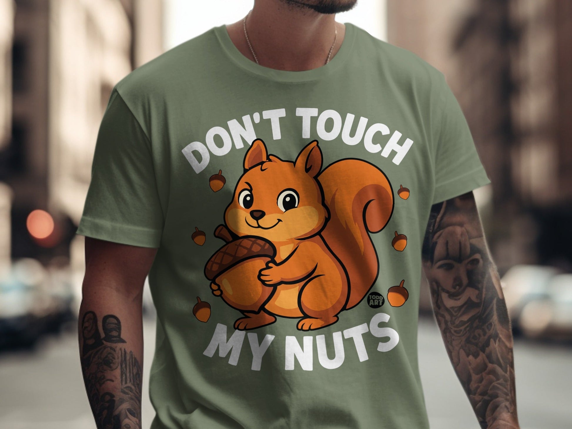Green t-shirt with a cartoon squirrel holding an acorn and text "DON'T TOUCH MY NUTS".