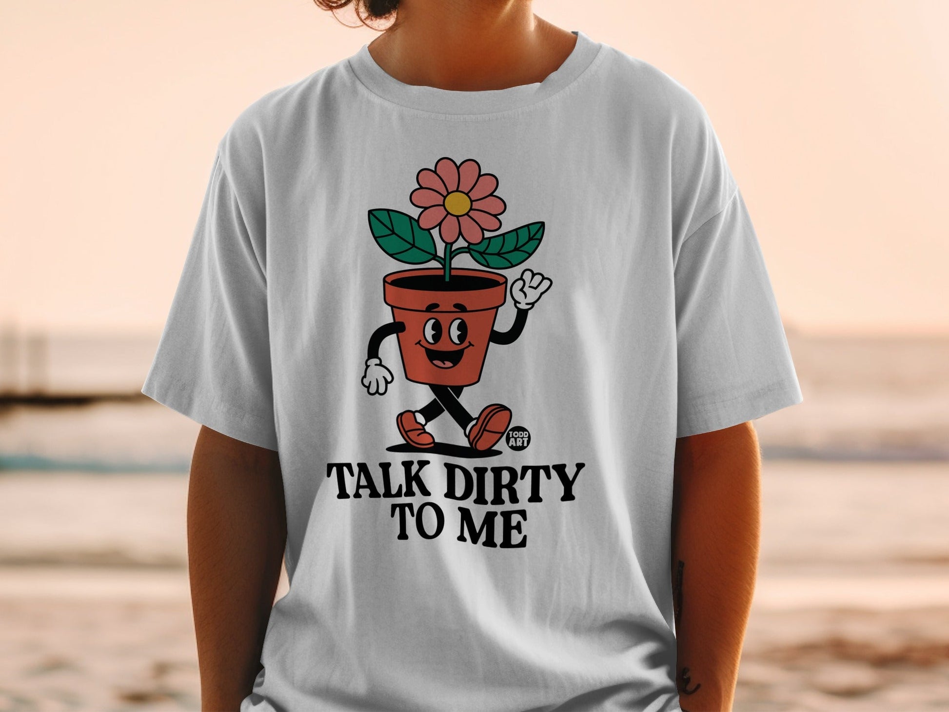 White t-shirt with a cartoon flower pot character and text "TALK DIRTY TO ME".