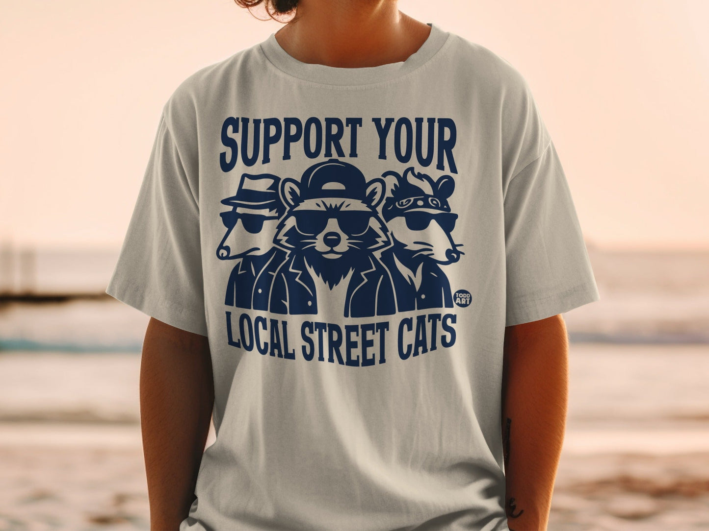 T-shirt graphic with three stylized cats in sunglasses and hats, text "SUPPORT YOUR LOCAL STREET CATS".