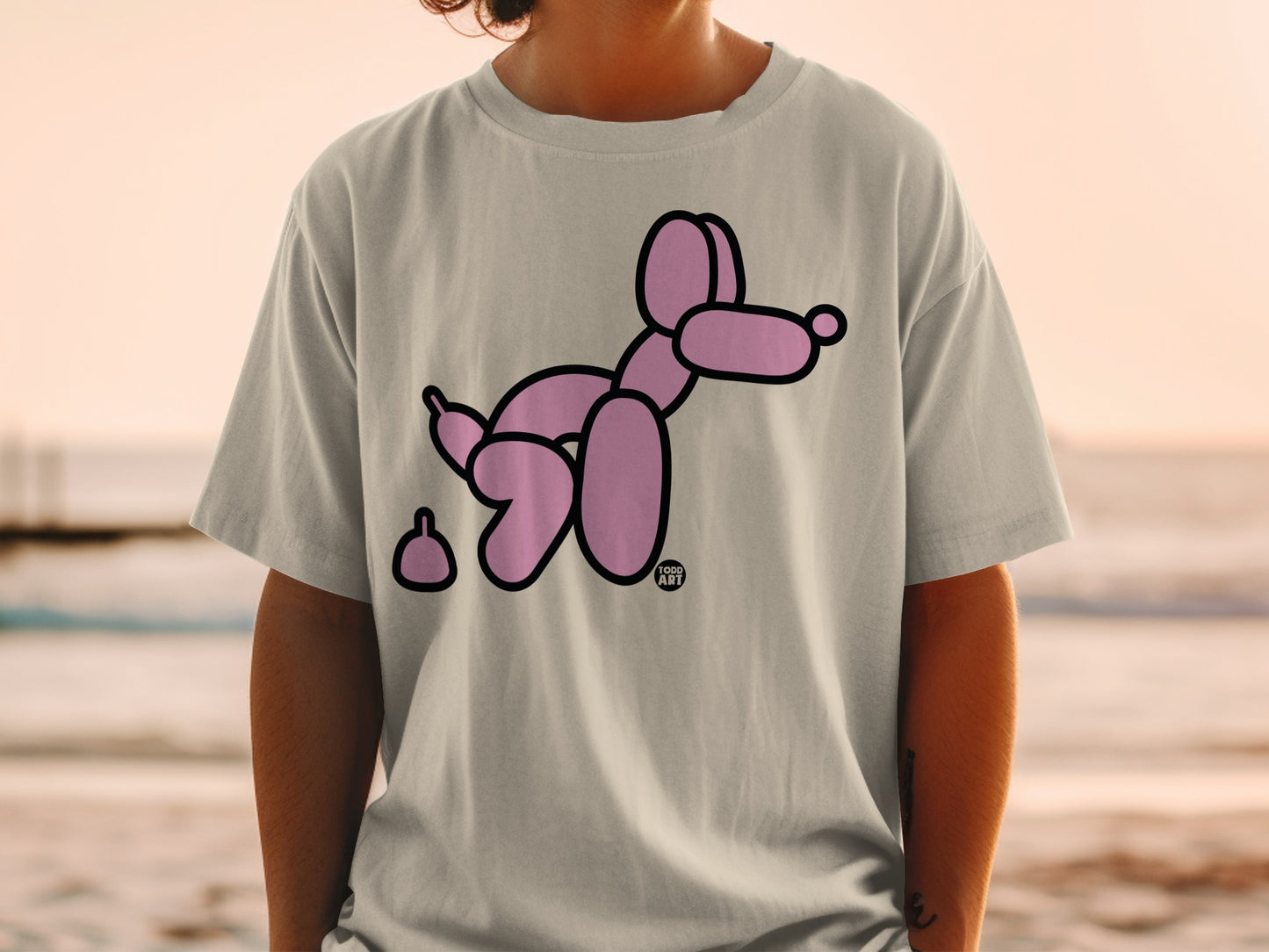 Pink balloon dog and poop design on a light grey t-shirt.