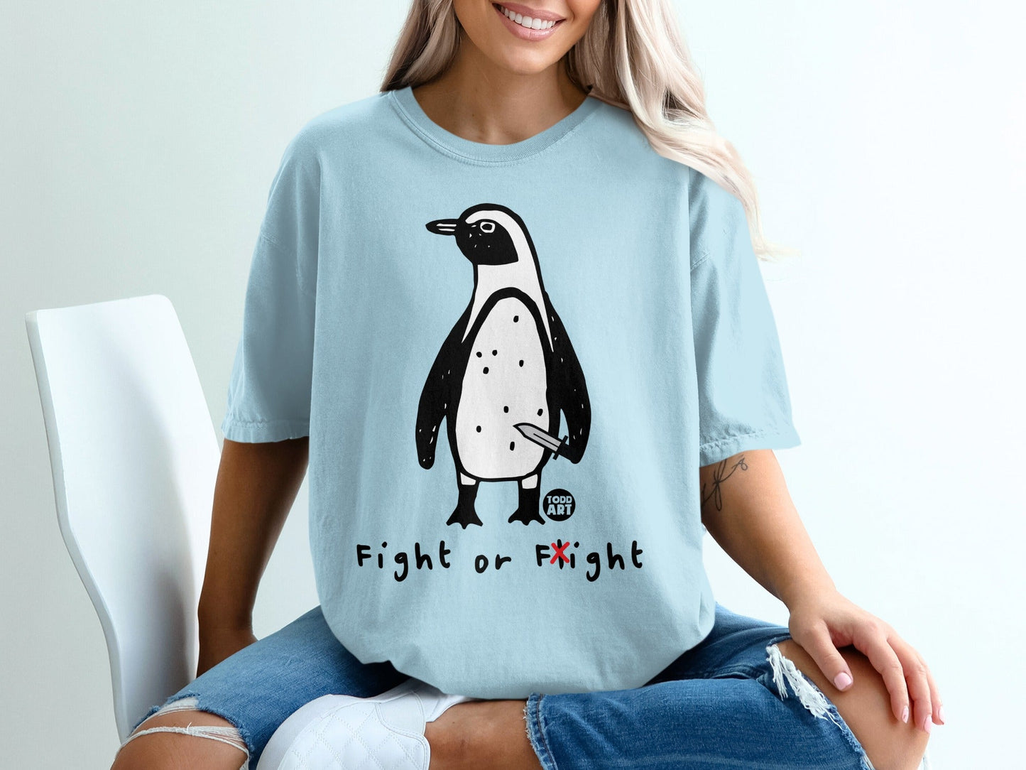 Light blue t-shirt with a cartoon penguin holding a knife, text reads "Fight or Flight".