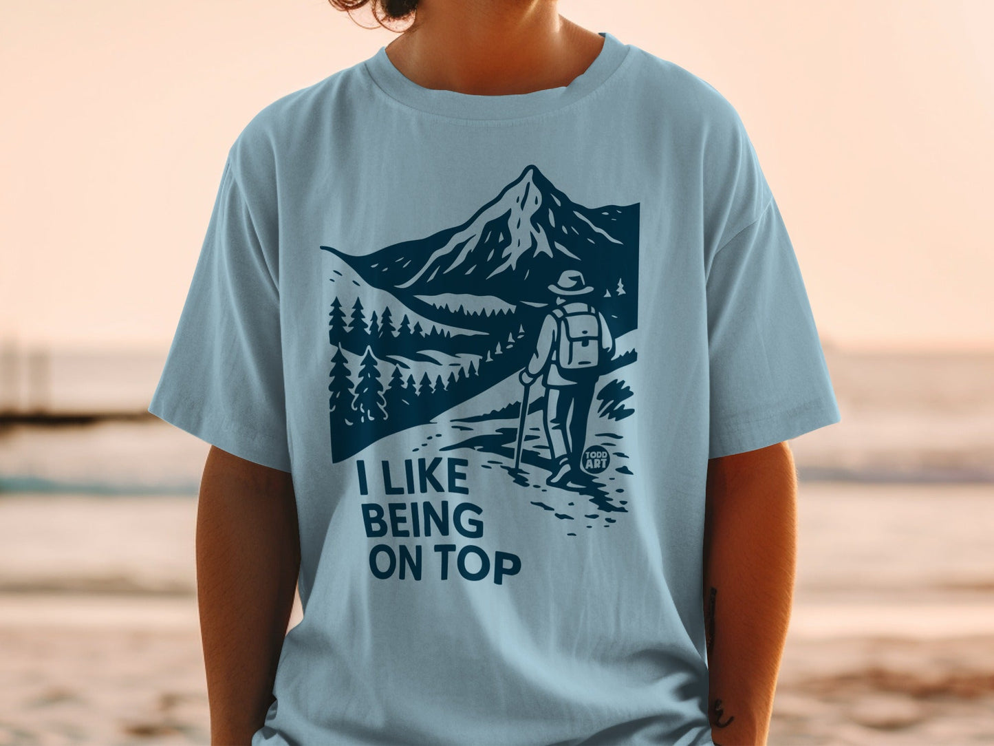 Light blue t-shirt with a dark blue graphic of a hiker and mountains.
