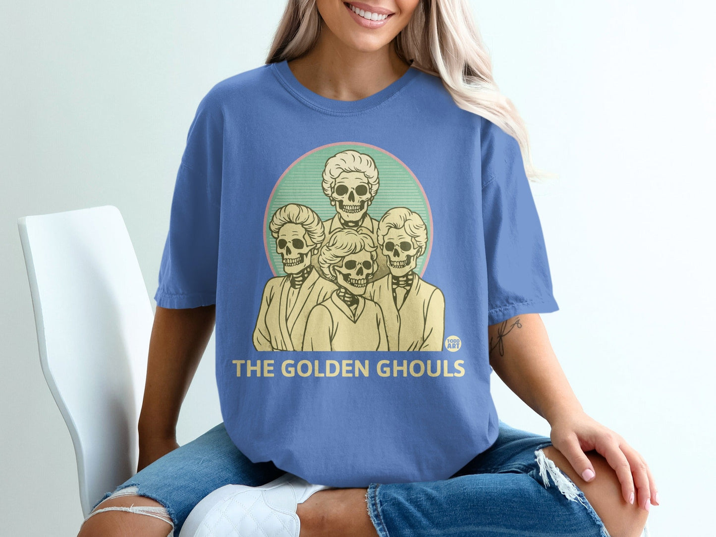 Blue t-shirt with graphic of four skeletons and text "The Golden Ghouls".