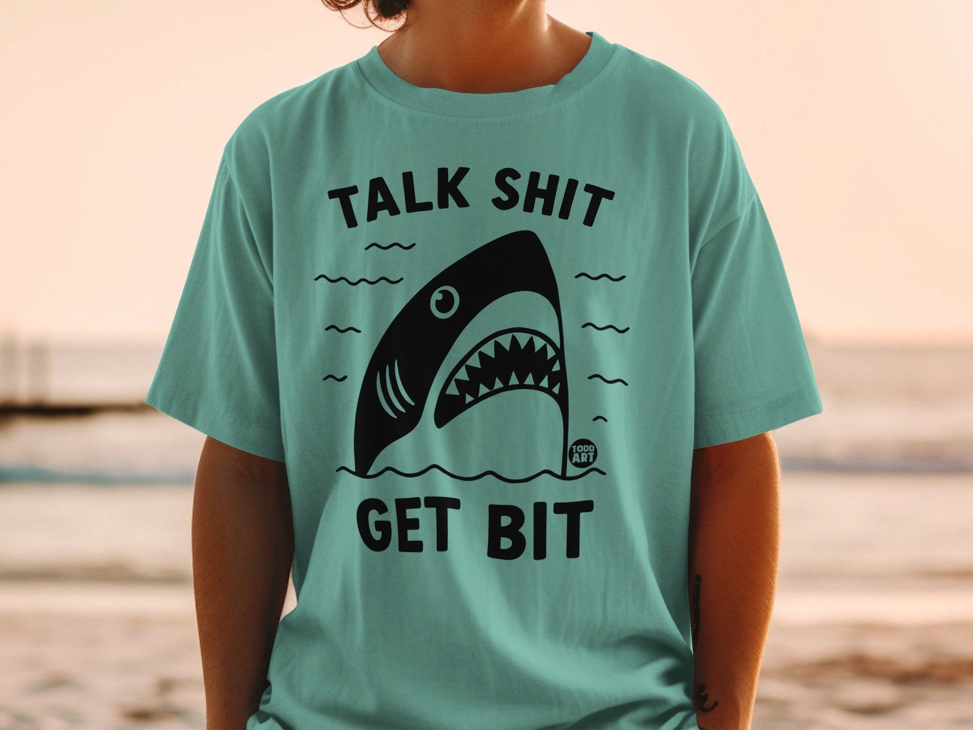 Teal t-shirt with a shark graphic and text "TALK SHIT GET BIT".