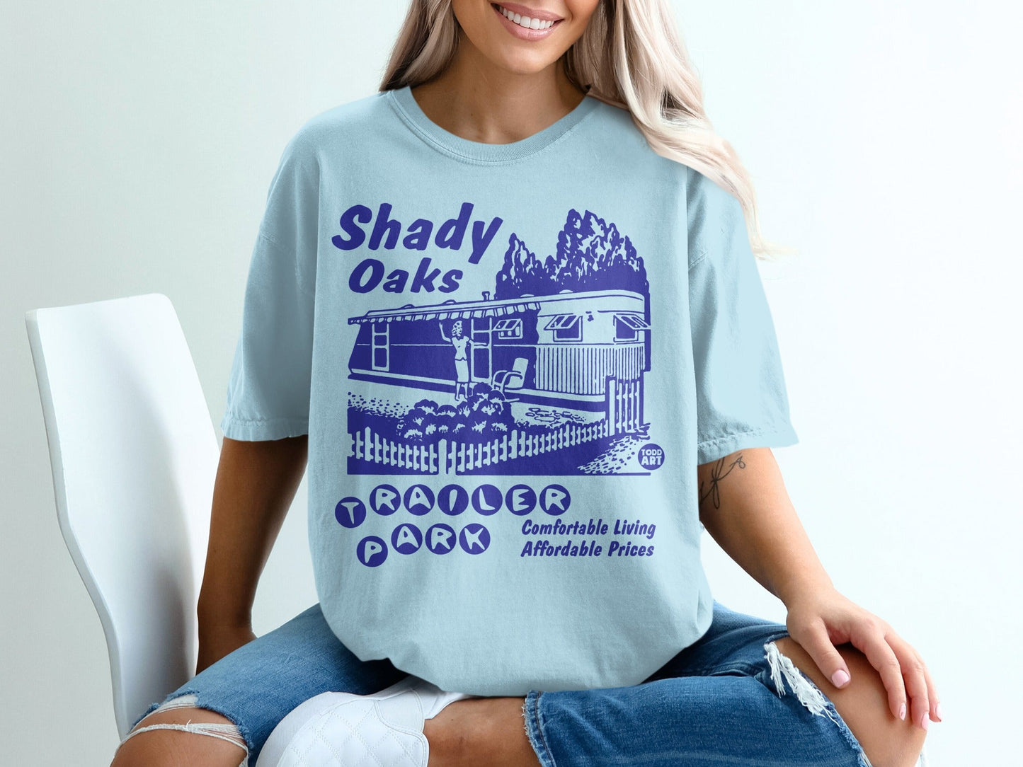 Shady Oaks Trailer Park graphic tee with blue text and caravan illustration.