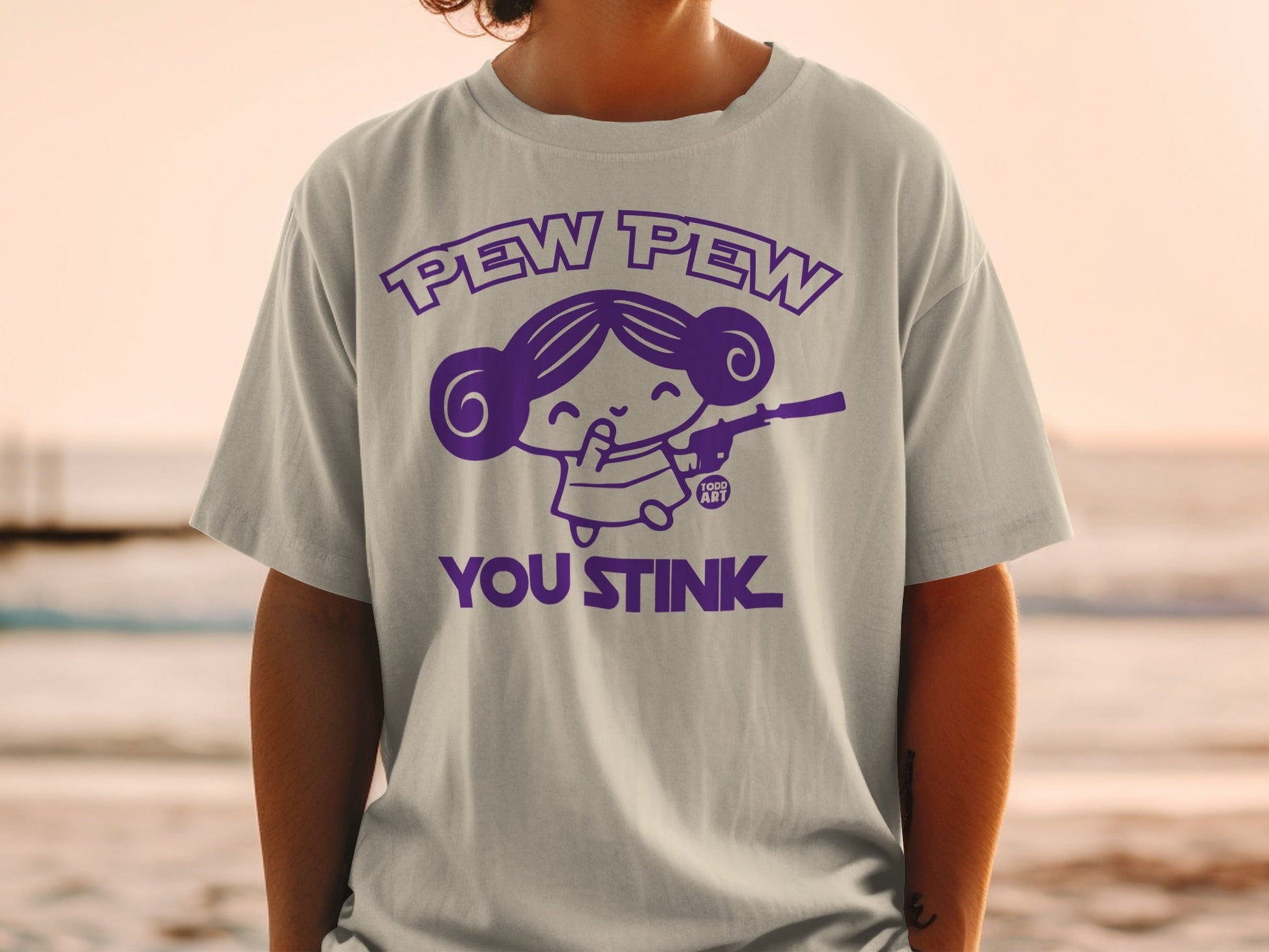 T-shirt with "Pew Pew You Stink" graphic of a girl with a gun.