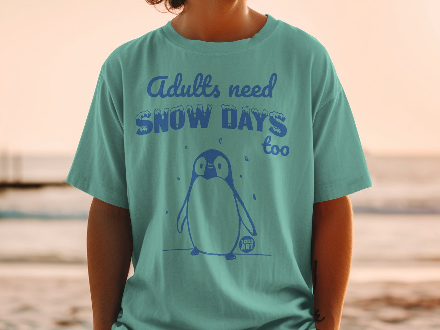 T-shirt with text "Adults need SNOW DAYS too" and a penguin graphic.
