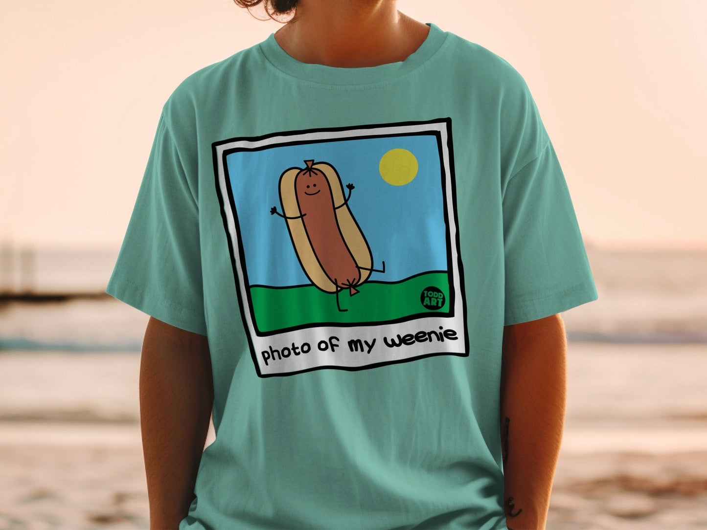 T-shirt with a cartoon hot dog in a bun, smiling, with the text "photo of my weenie".